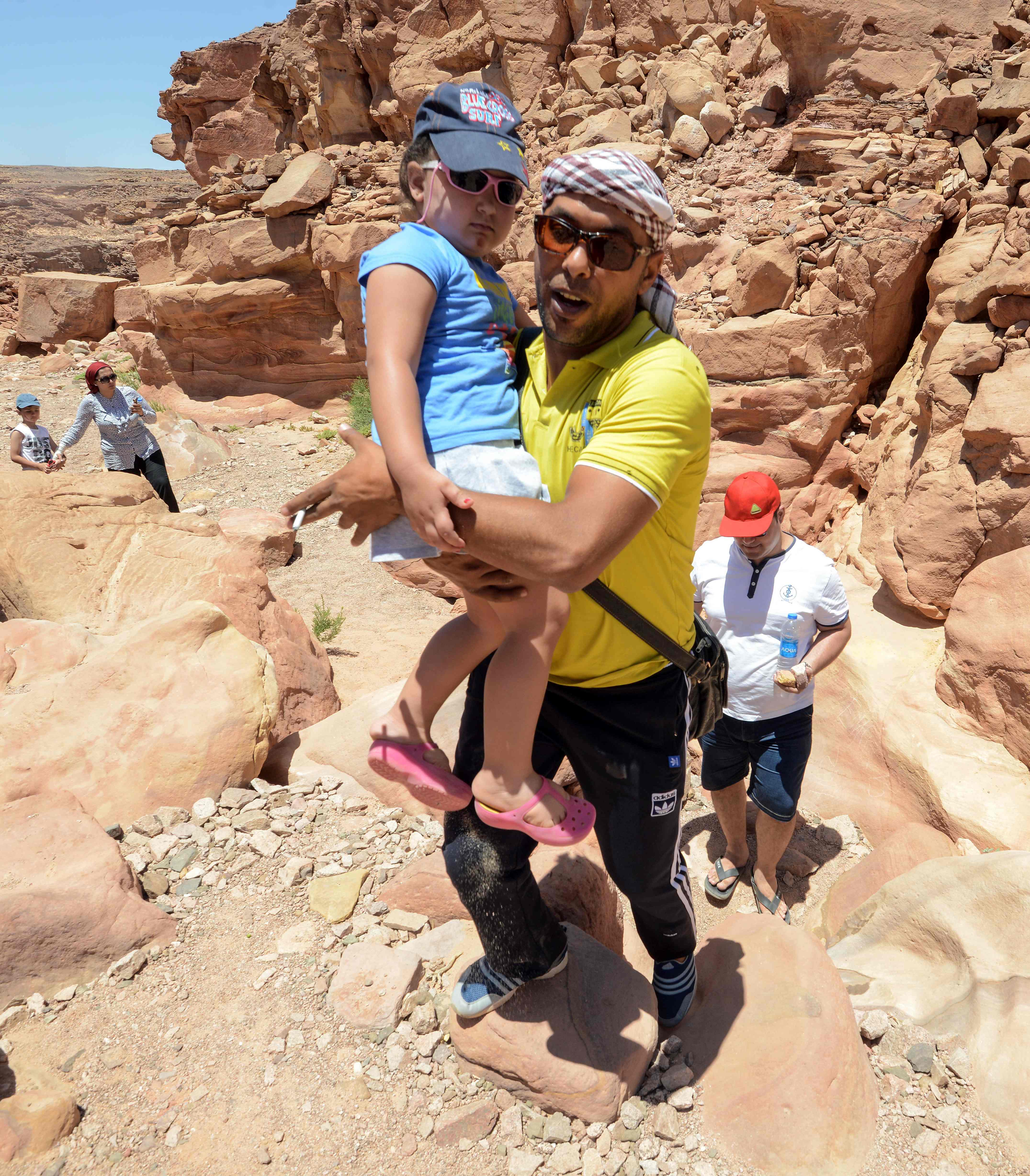 رجل يحمل طفلة ليساعدها على تسلق المرتفعات