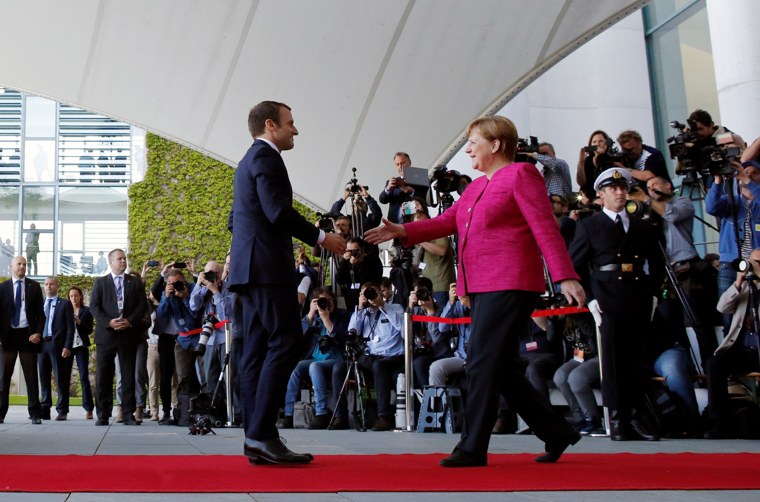 المستشارة الألمانية أنجيلا ميركل تصافح الرئيس الفرنسي إيمانويل ماكرون  لدى زيارته برلين