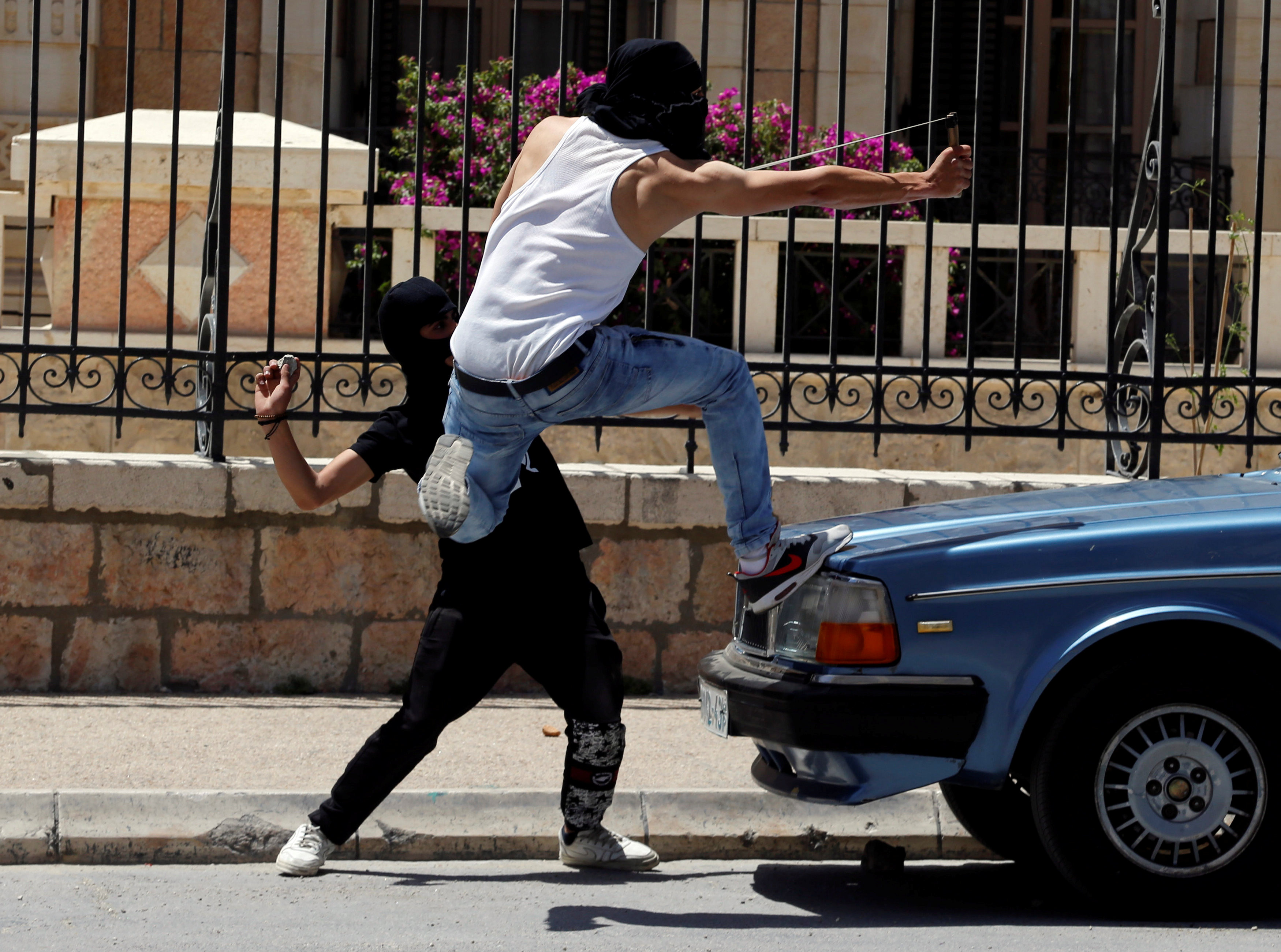 شاب يقذف الطوب على قوات الاحتلال باستخدام النبال