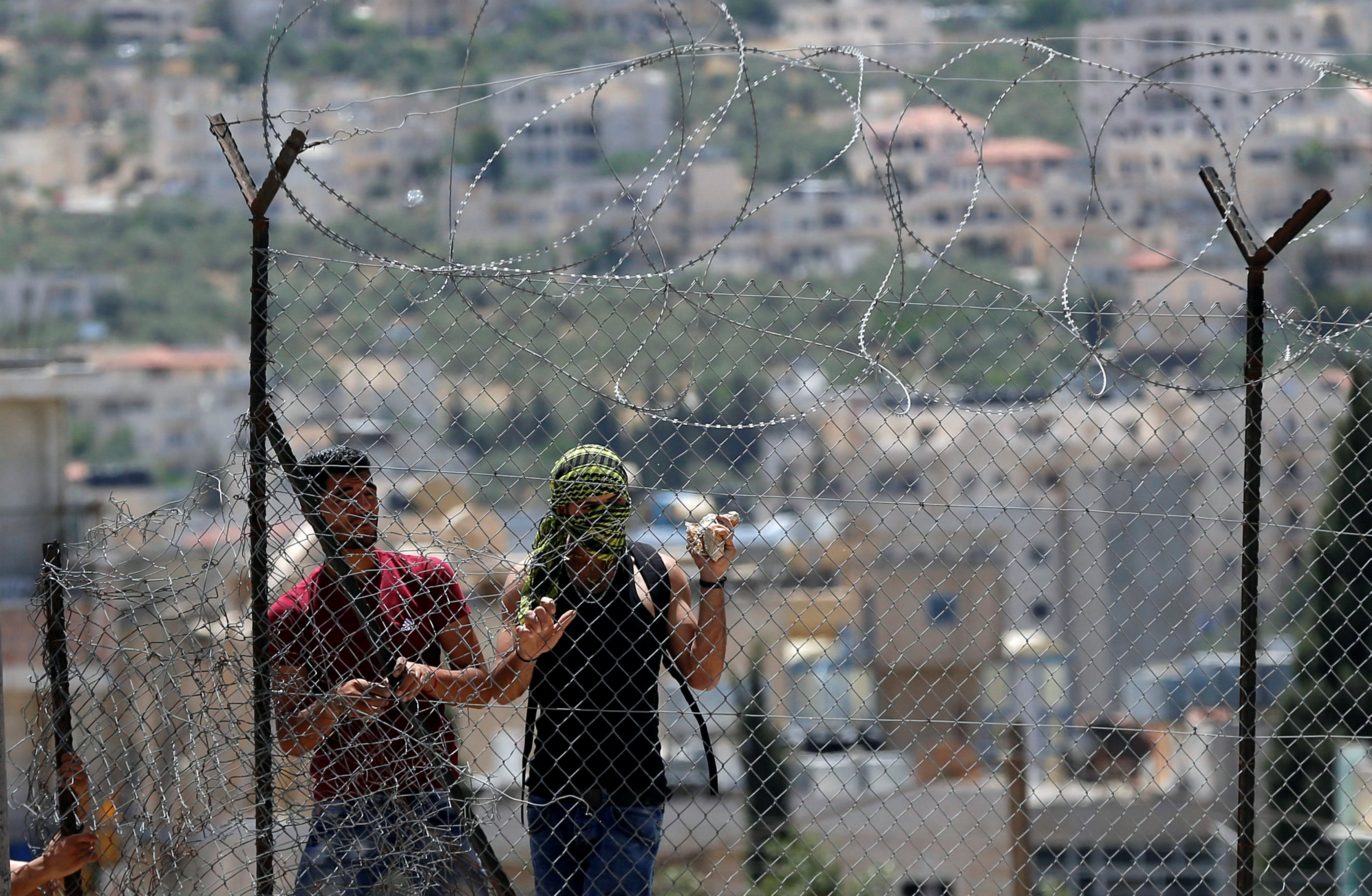 شباب خلف السياج الحديدى خلال مواجهة قوات الاحتلال