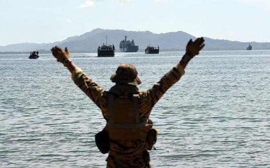 جندى-يشير-إلى-القوارب-والسفن-الحربية-من-الشاطئ