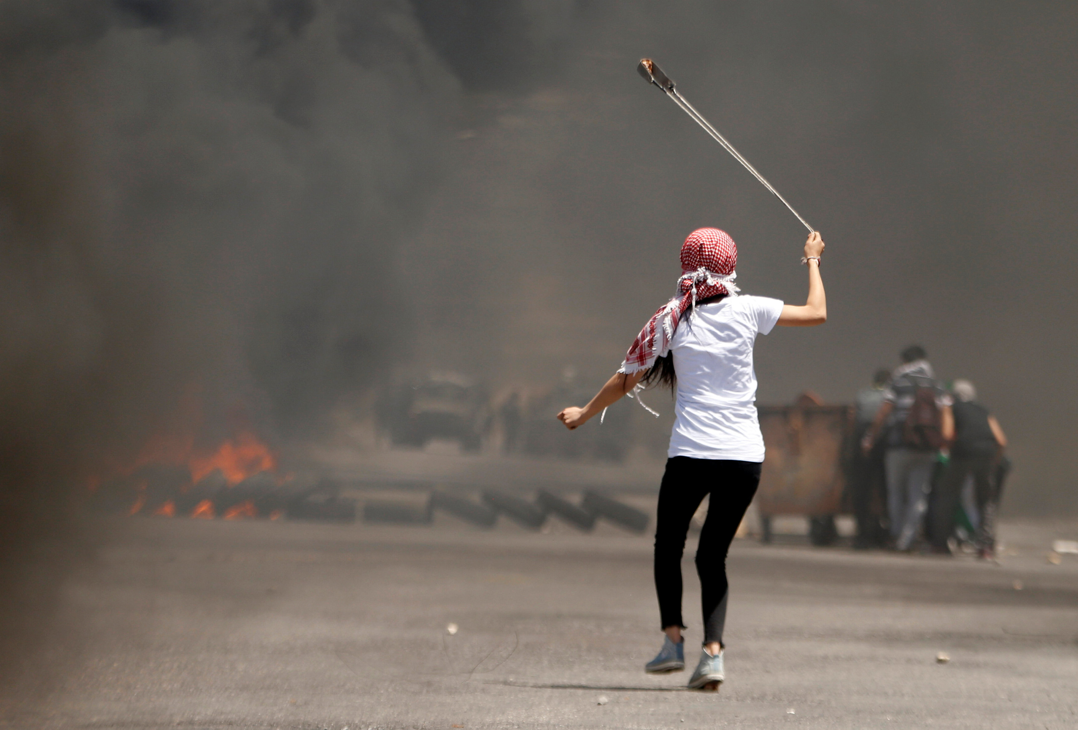فتاة تلقى الحجارة على قوات الاحتلال