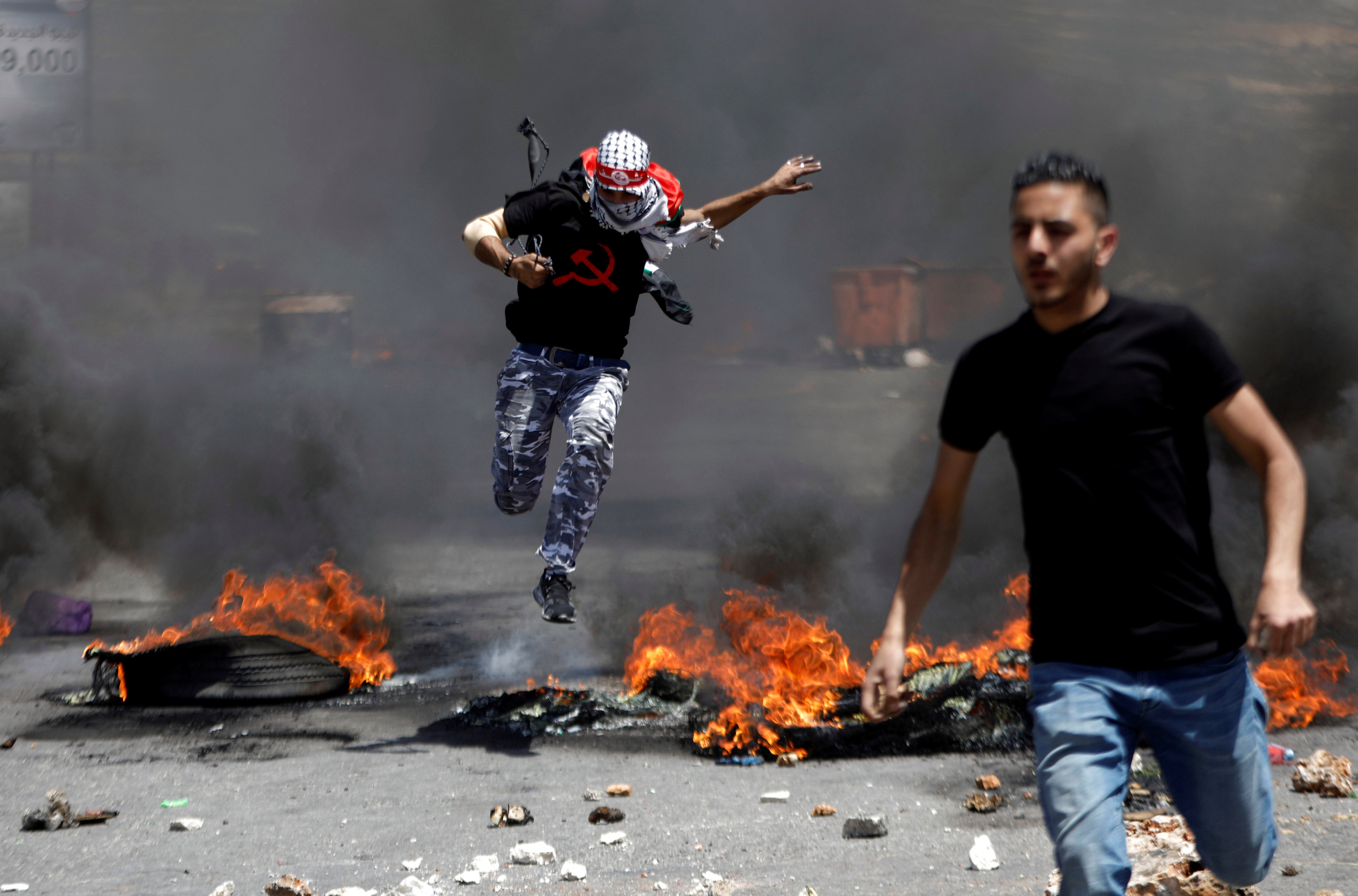 شاب يقفز أعلى النار خلال مواجهات مع قوات الاحتلال