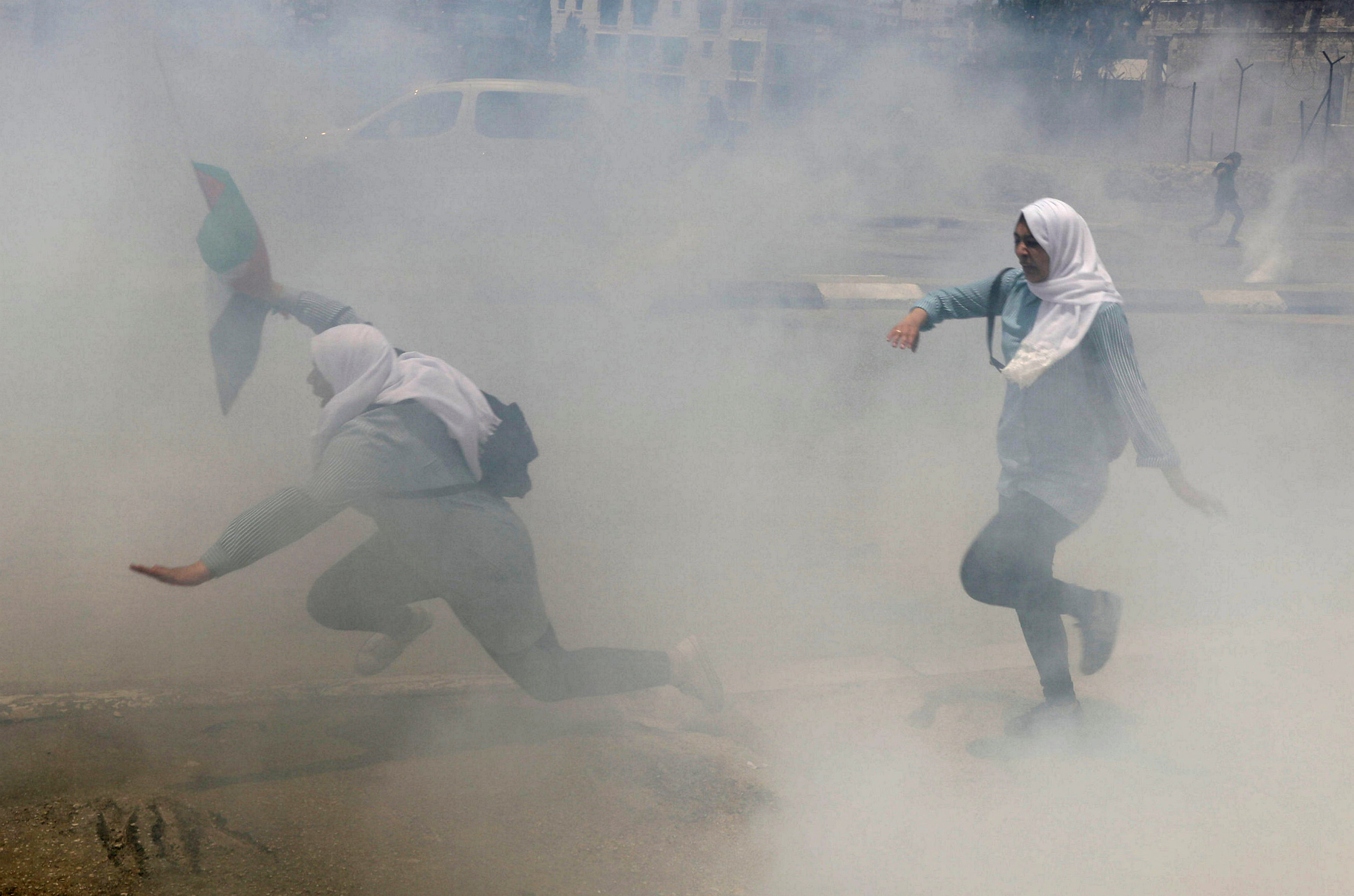 طالبات فلسطينيات يهربن من دخان الغاز المسيل للدموع