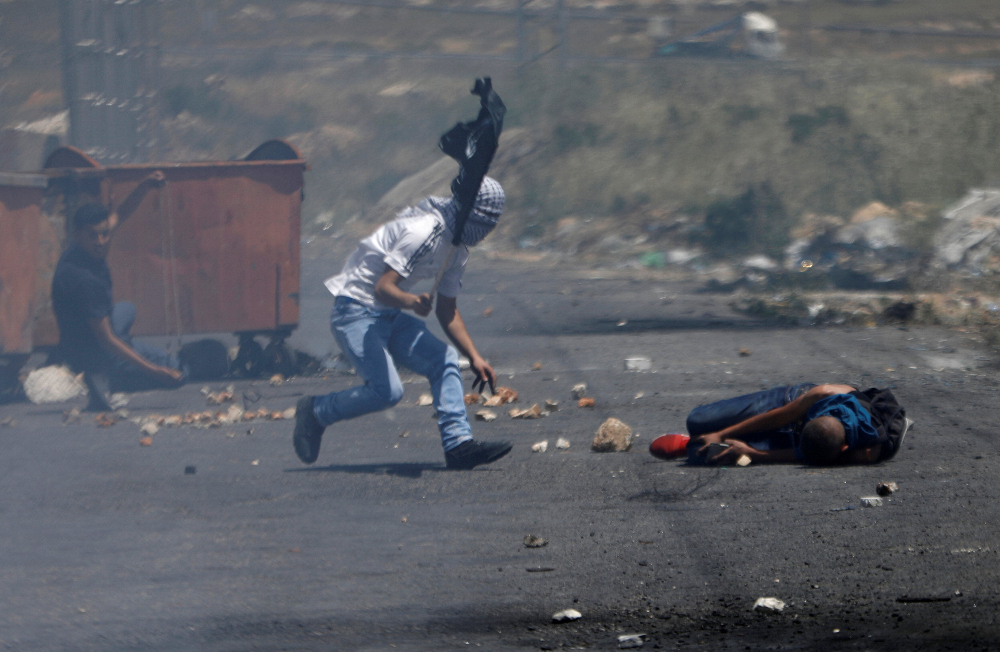 شاب يحاول انقاذ صديقه المصاب فى مواجهات قوات الاحتلال