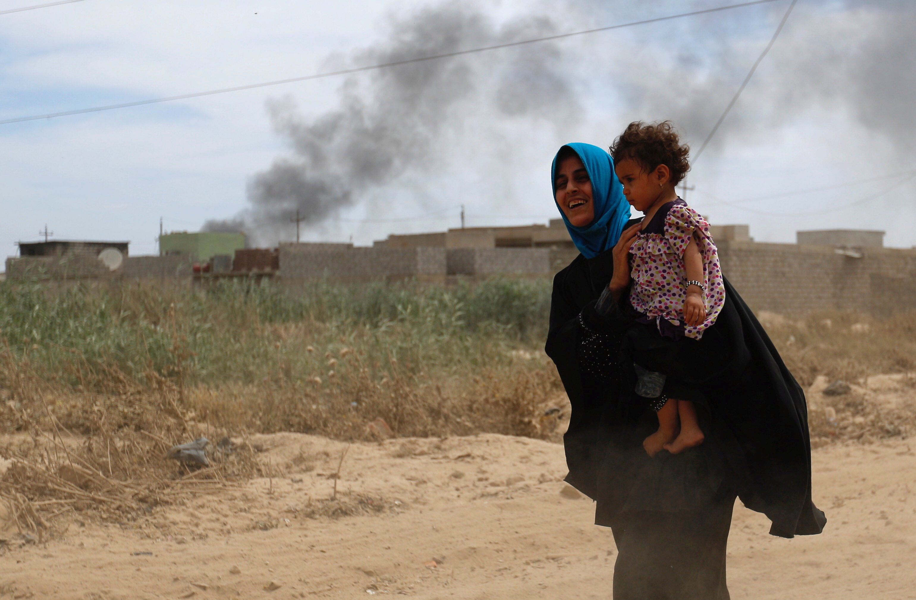 امرأة عراقية تحمل طفلها بعد فرارها من مدينة الموصل