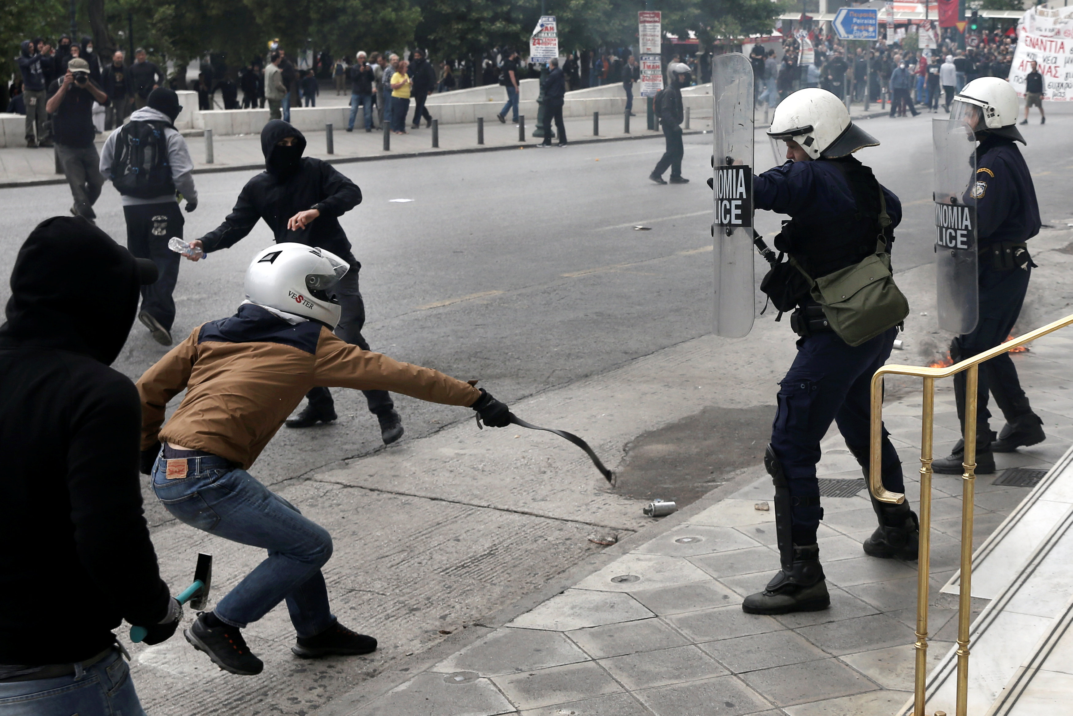 متظاهر يونانى يضرب أحد أفراد الشرطة بالحزام
