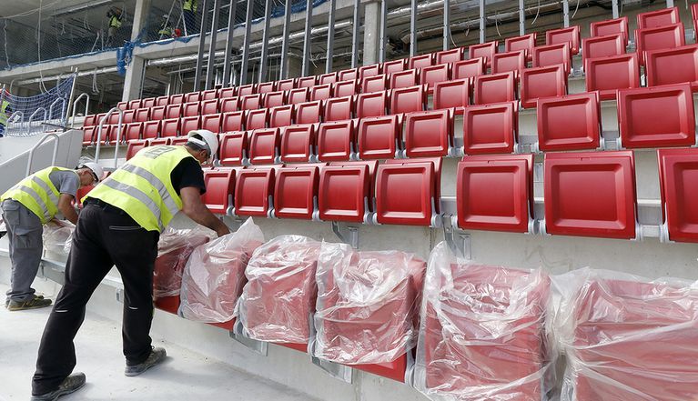 العمال يضعون الكراسى الحمراء فى الملعب الجديد