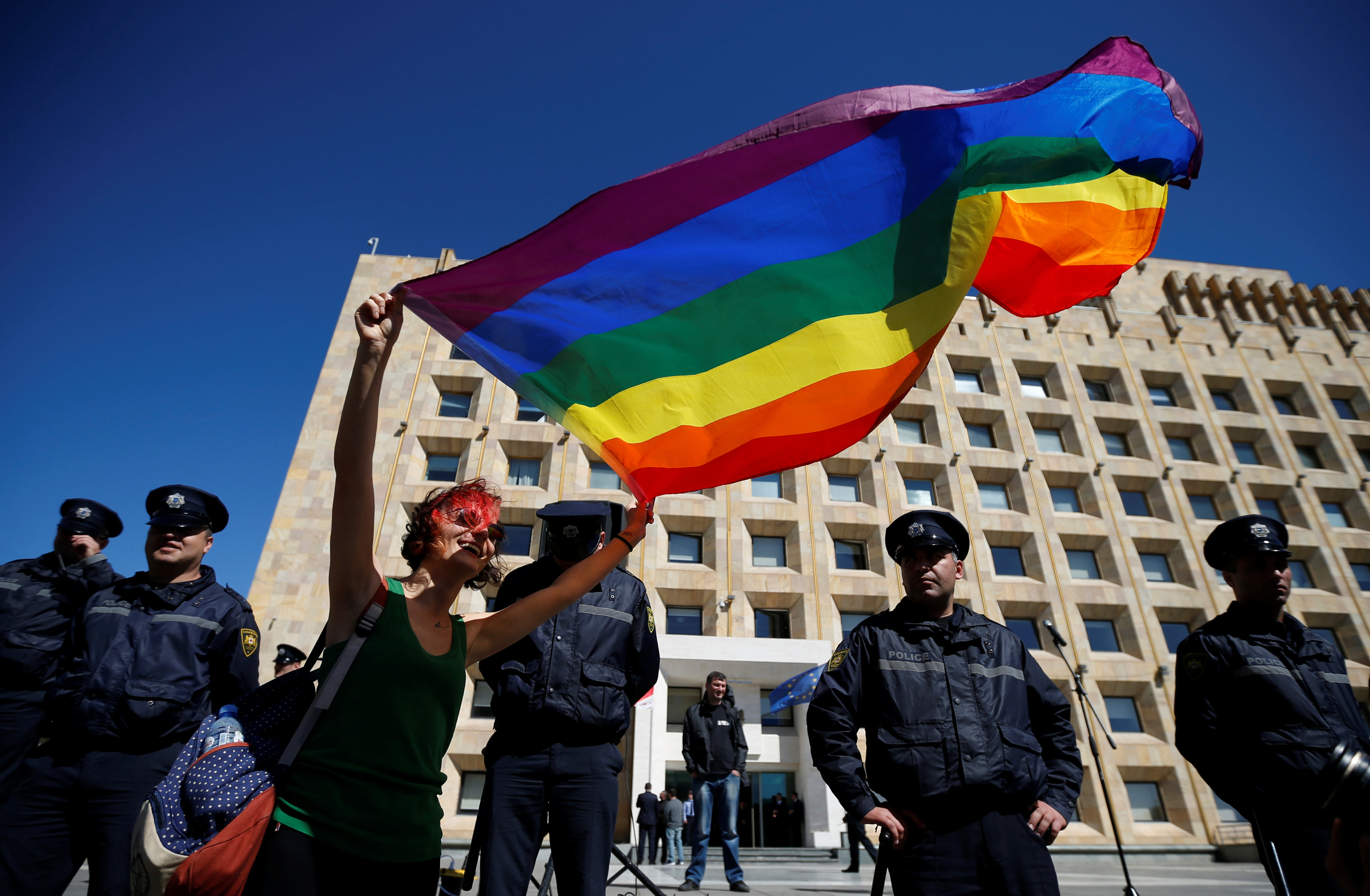متظاهرة تحمل علم المثليين أمام قوات الأمن