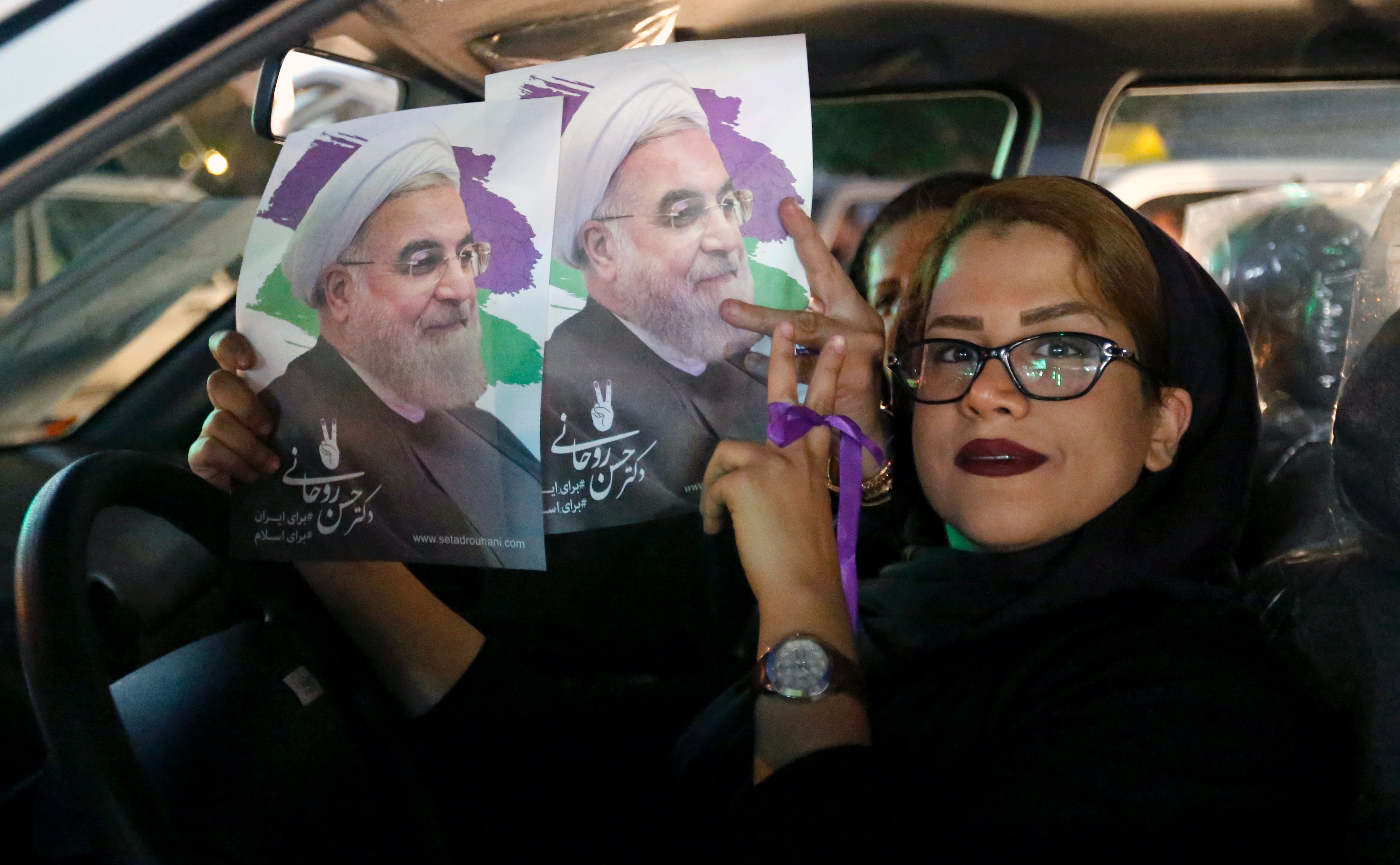 إيرانية تحمل صور لروحانى قبل انطلاق الانتخابات