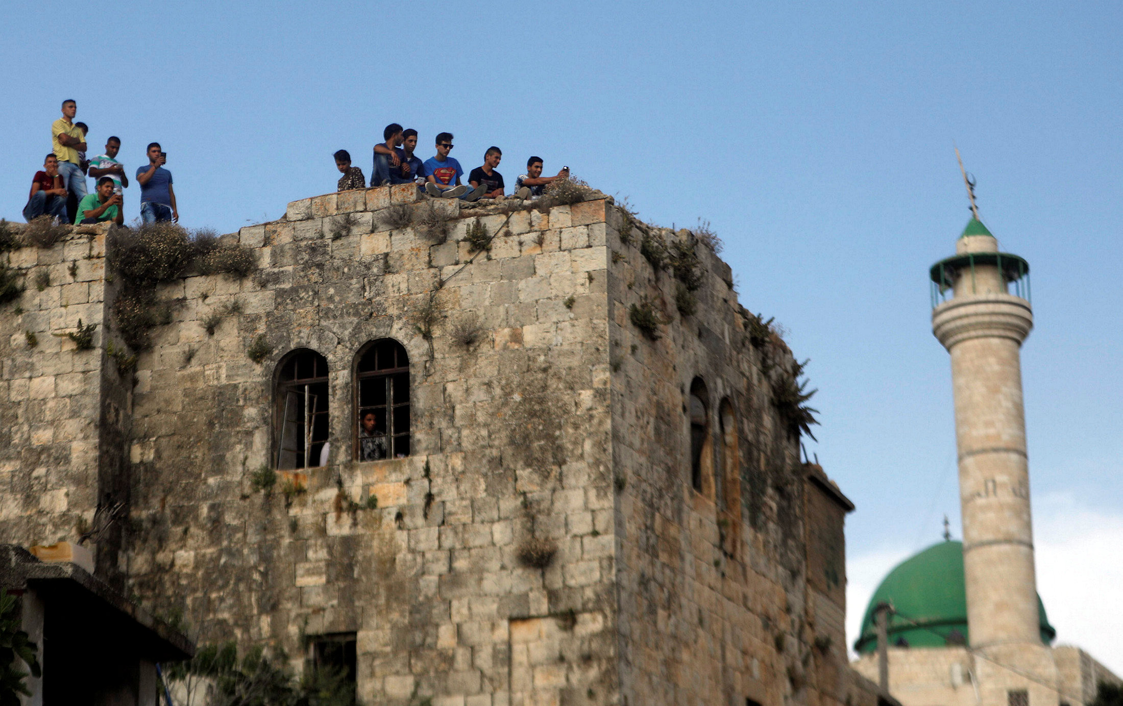 شباب فلسطينيين على سطح أحد المبانى أثناء الجنازة