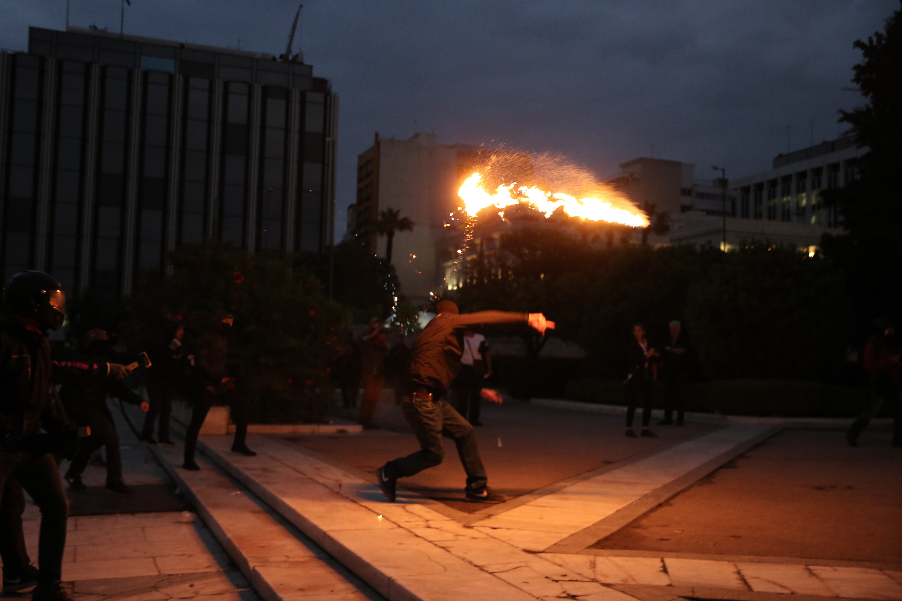 متظاهر يلقى كرات اللهب على شرطة مكافحة الشغب اليونانية