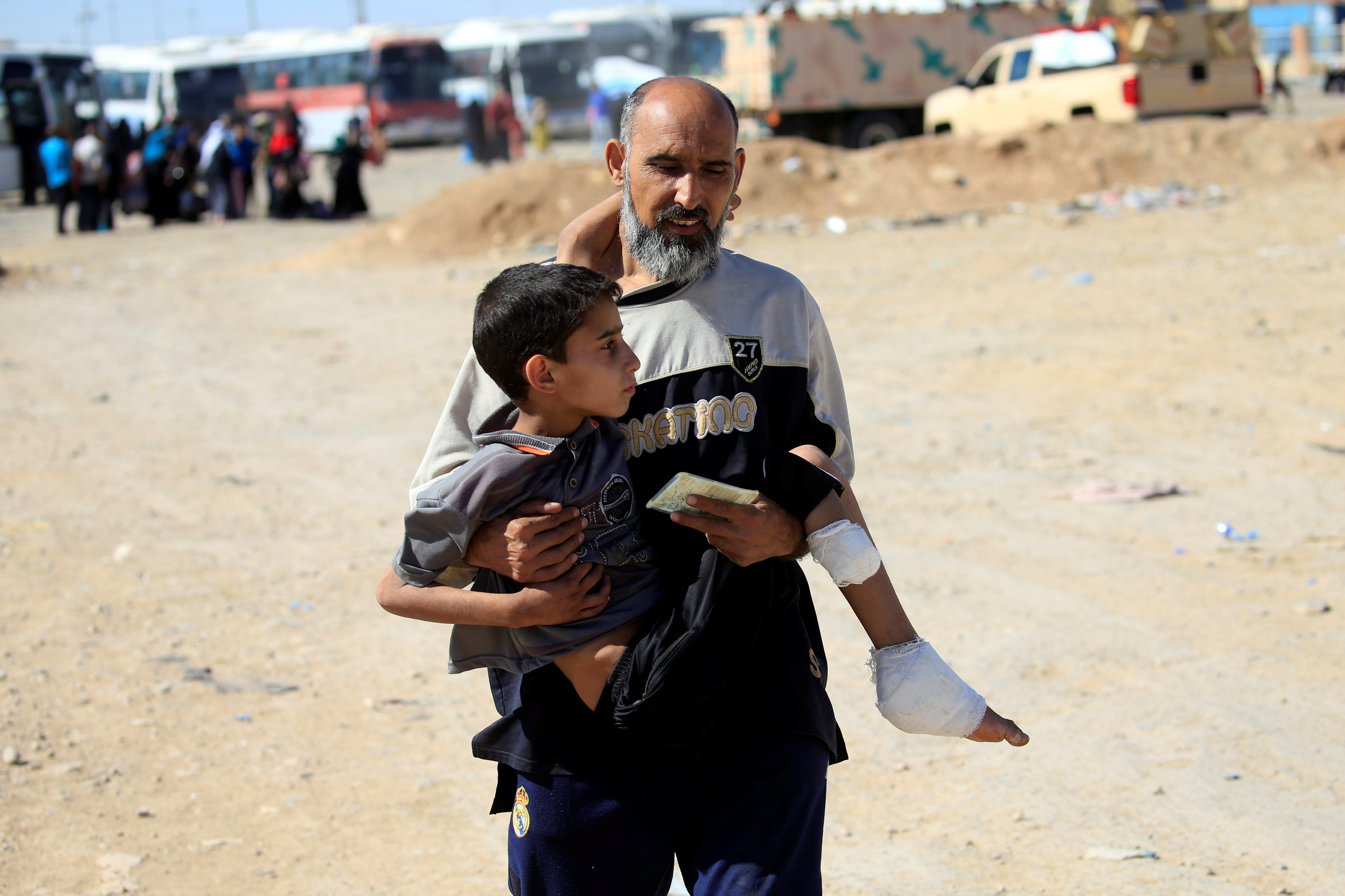 رجل يحمل نجله خلال النزوح من الموصل