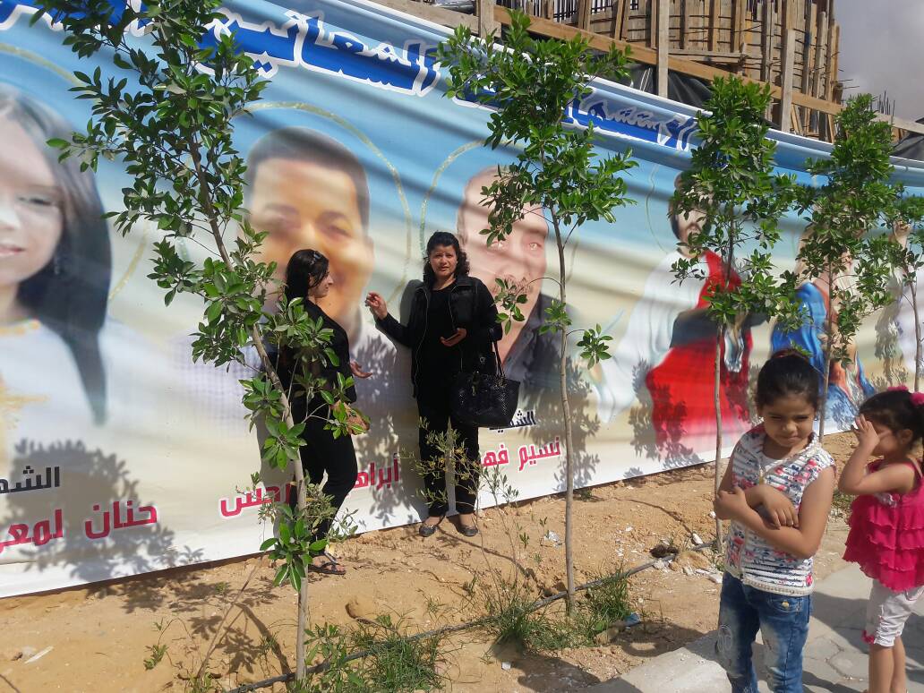 سيدتان أمام لافتة تحمل صور الشهداء