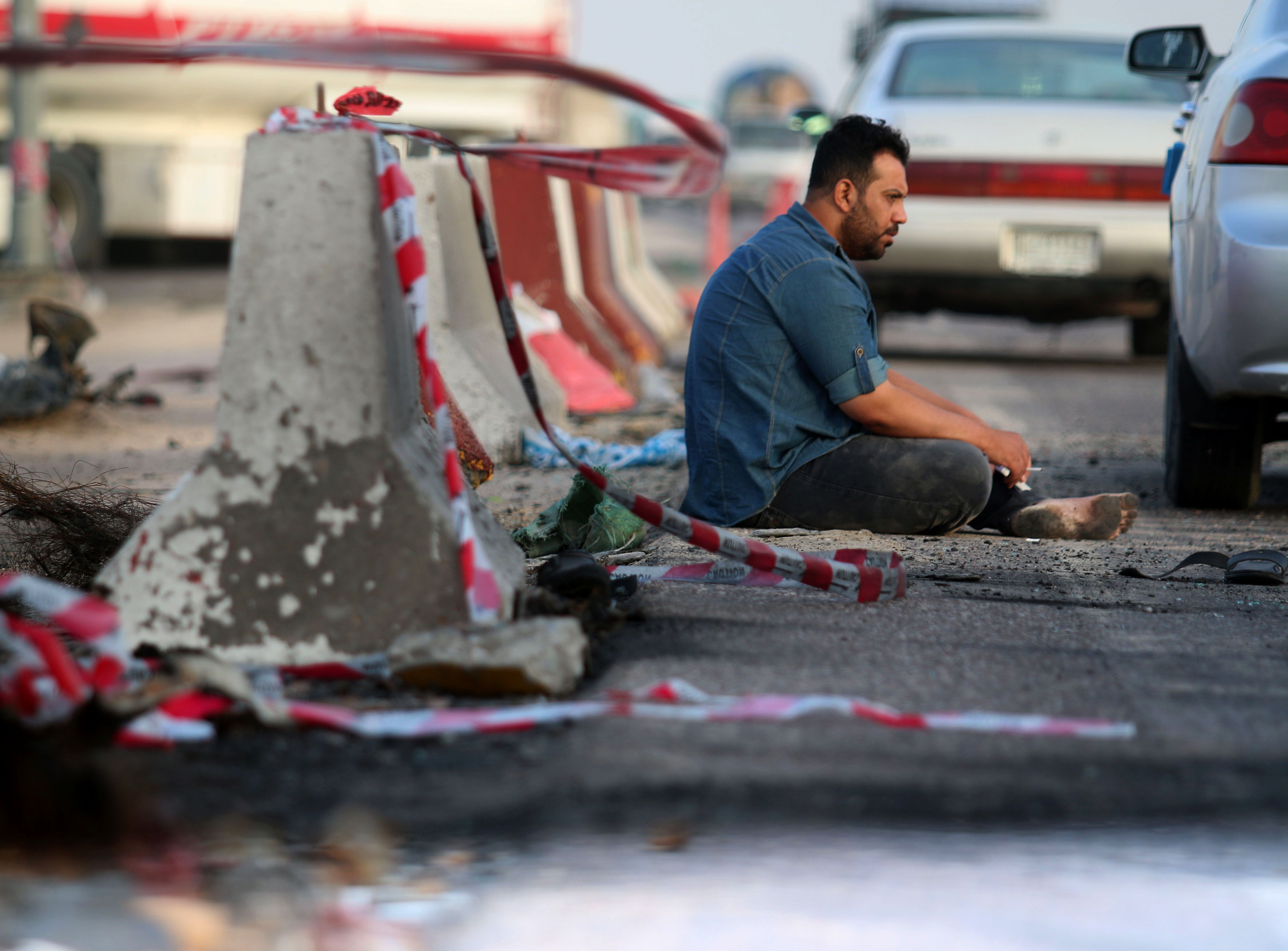 مواطن عراقى يجلس على الأرض بجانب الحواجز عقب التفجير