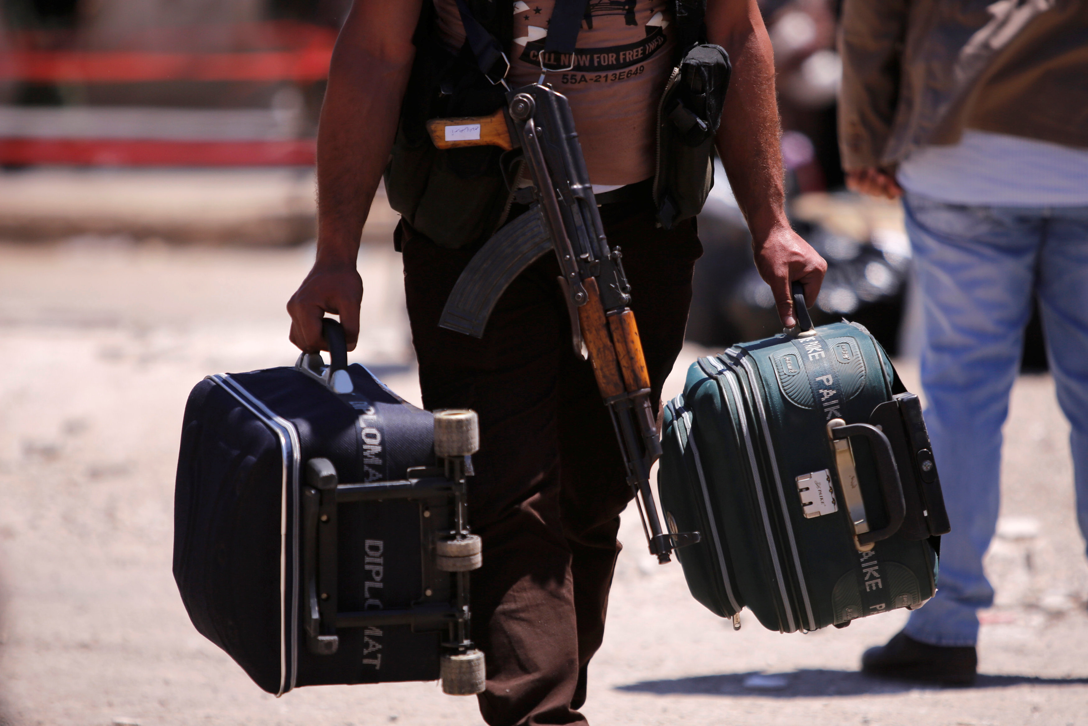 أحد المقاتلين يحمل حقائبه وسلاحه خلال مغادرته حمص