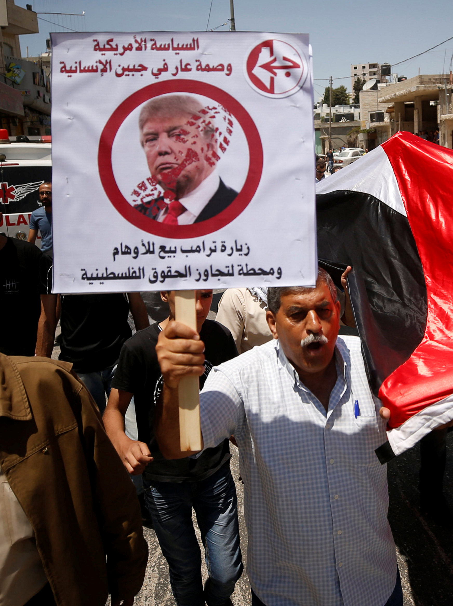فلسطينى يرفع لافتة تندد بزيارة ترامب