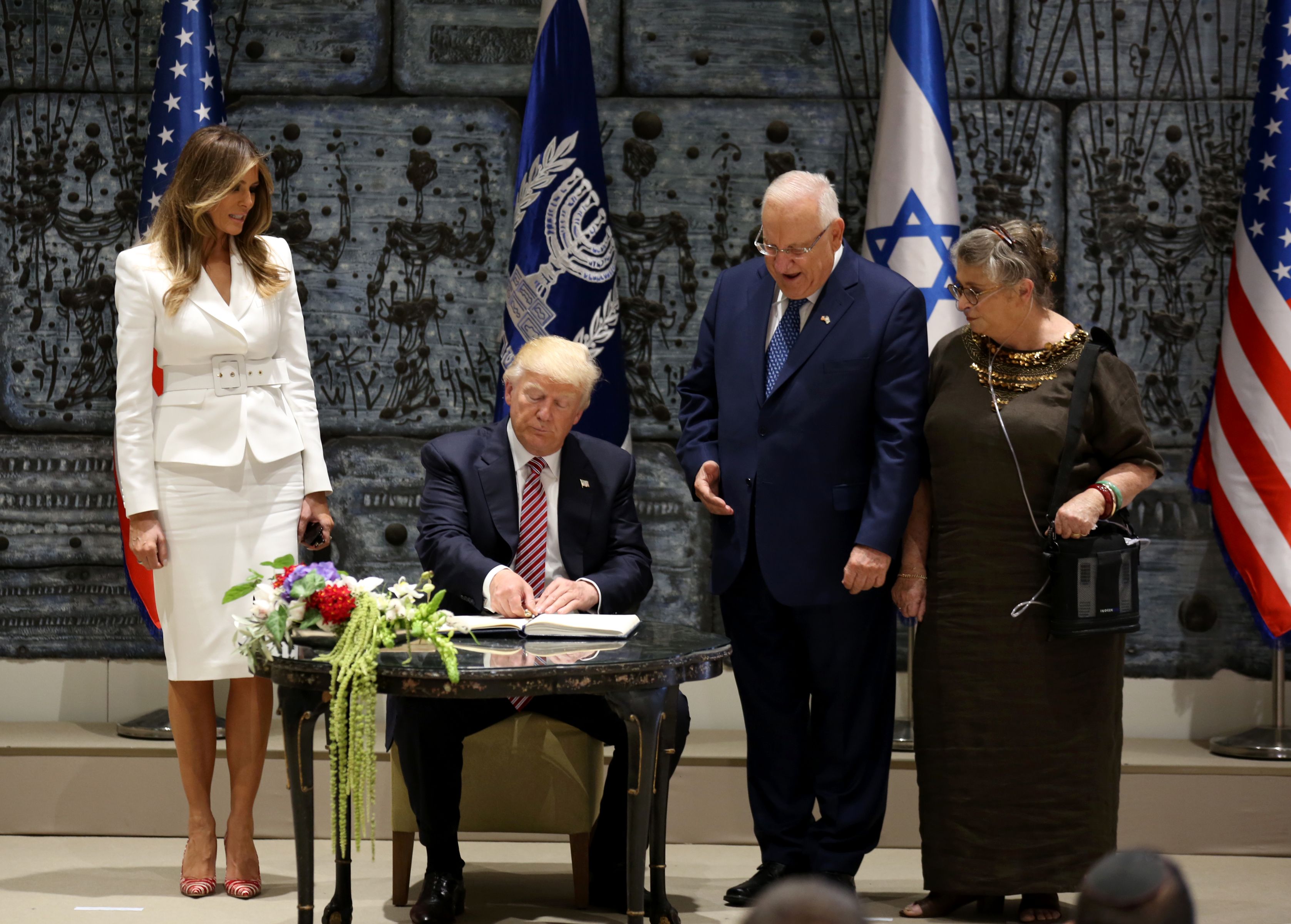 الرئيس الإسرائيلى وزوجته بجوار ترامب أثناء توقيعه فى الدفتر
