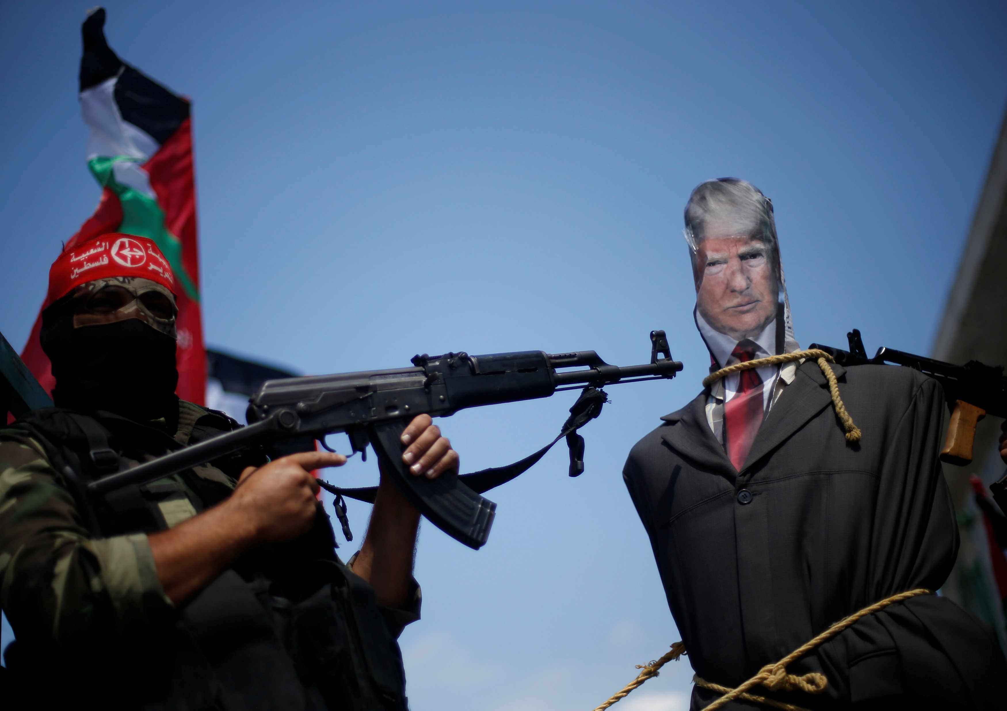 مقاتل بالمقاومة الفلسطينية يرفع سلاح آلى فى وجه مجسم لترامب