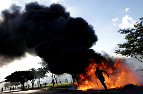 أحد المتظاهرين يشعل النيران خلال الاحتجاجات لمنع تقدم الشرطة
