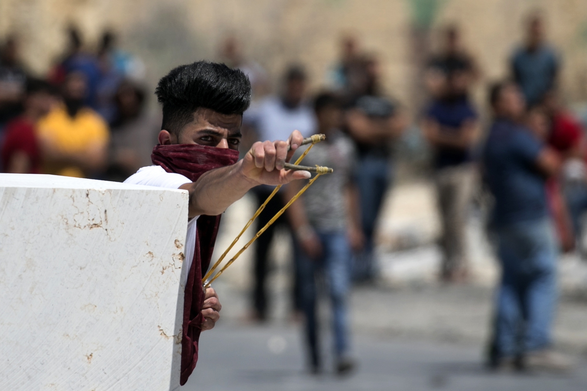شاب يطلق الحجارة علي قوات الاحتلال