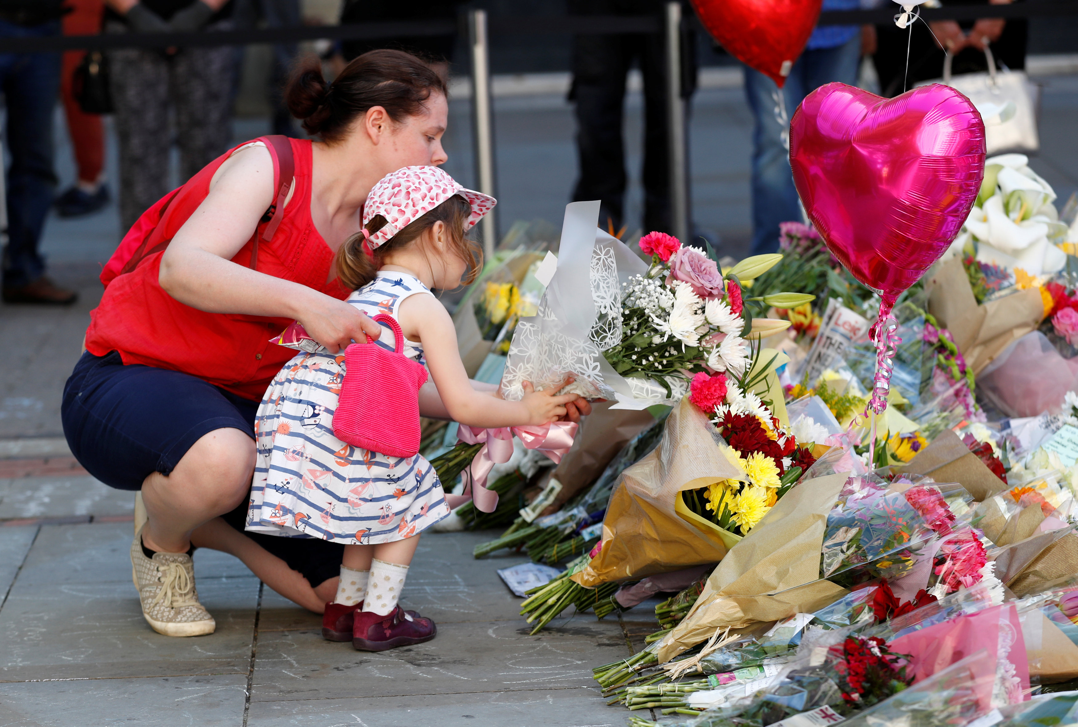 طفلة تضع باقة ورد لتأبين ضحايا هجوم مانشستر