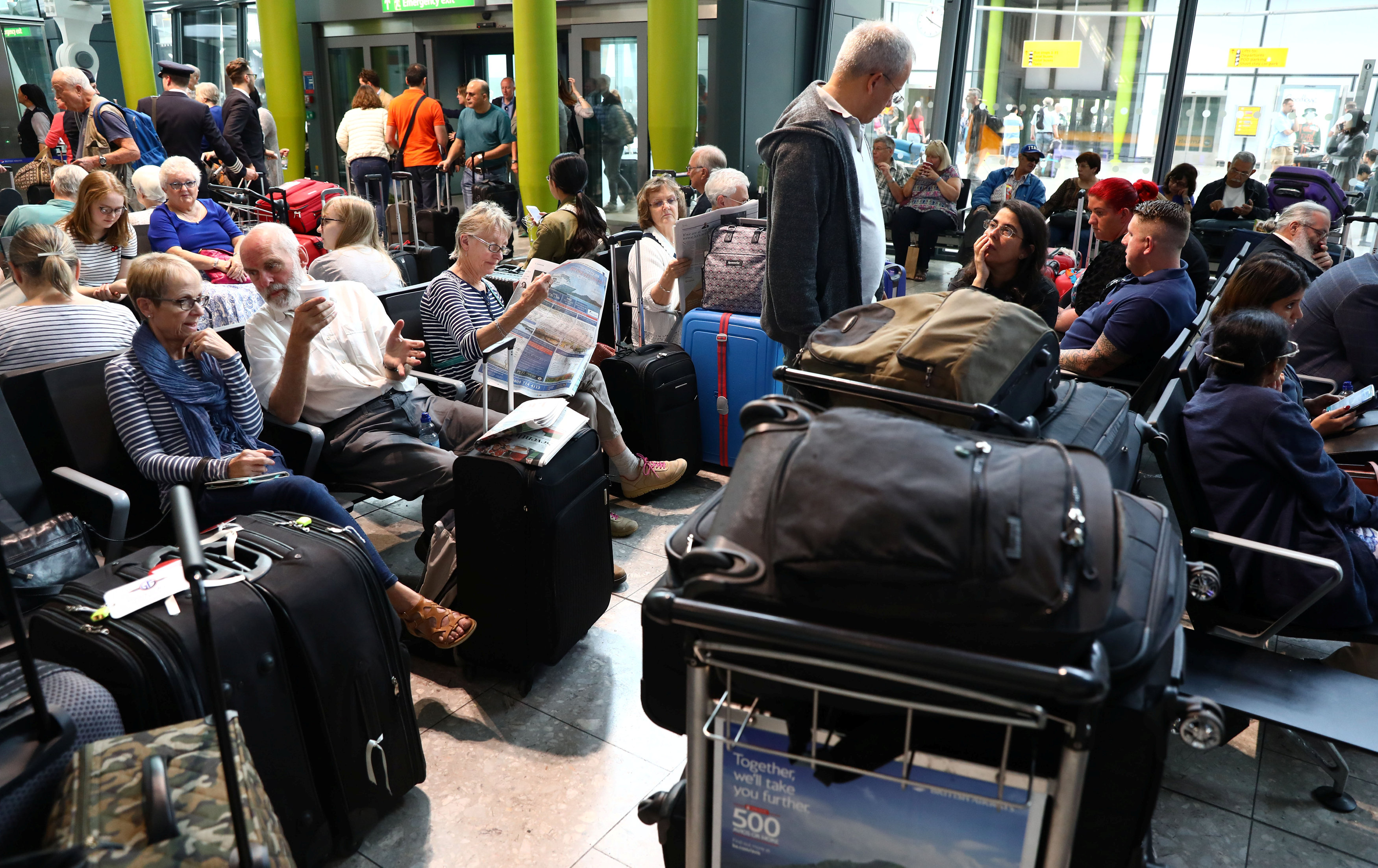 المسافرون يقرأون الصحف ويتبادلون الحديث بمطار هيثرو