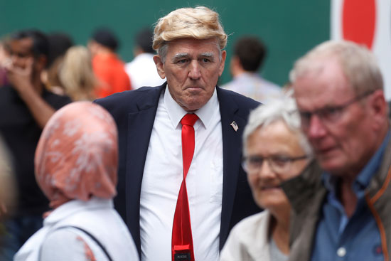 سيدة تلتقط صورة تذكارية مع شبيه ترامب