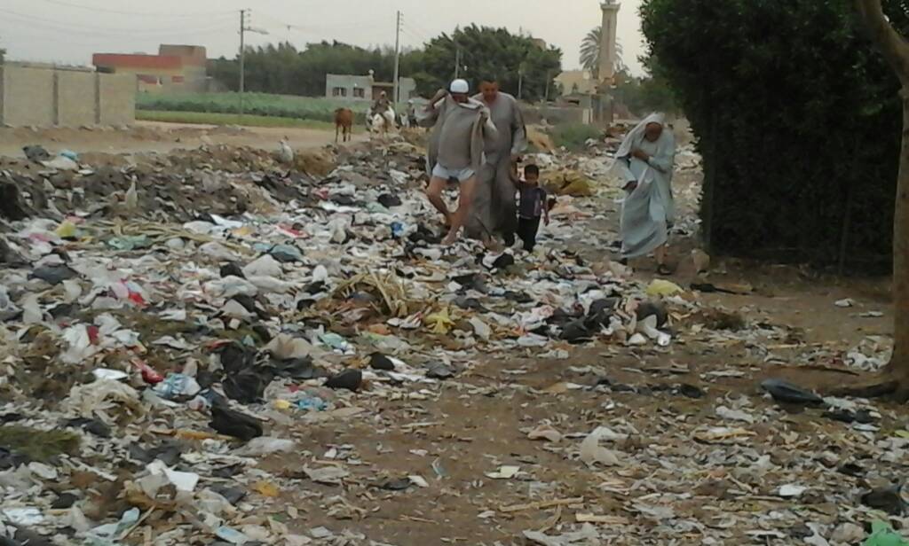 المواطنون يعبرون الطريق فوق القمامة