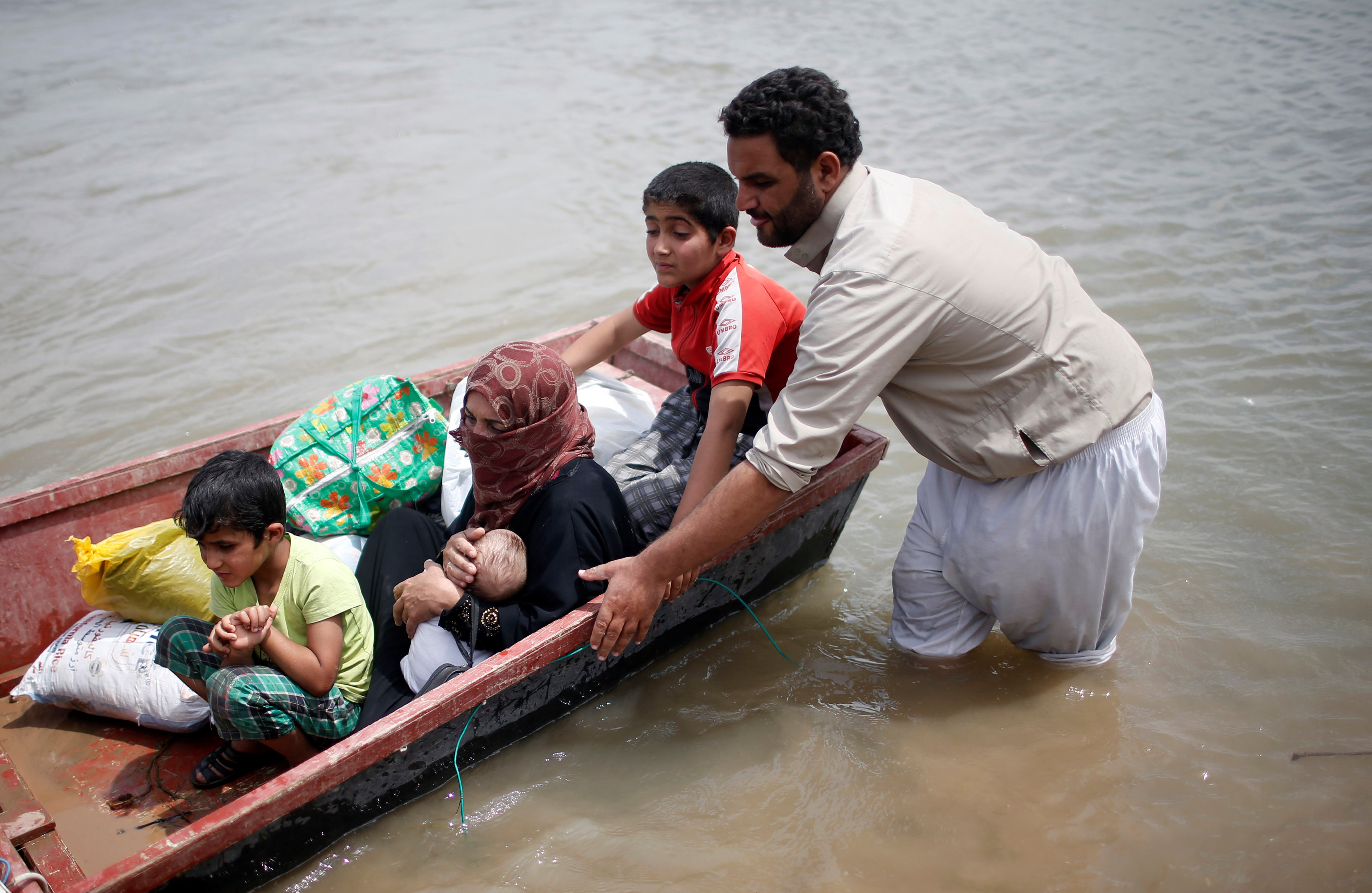 رجل يحاول إنقاذ اسرته من الفيضان