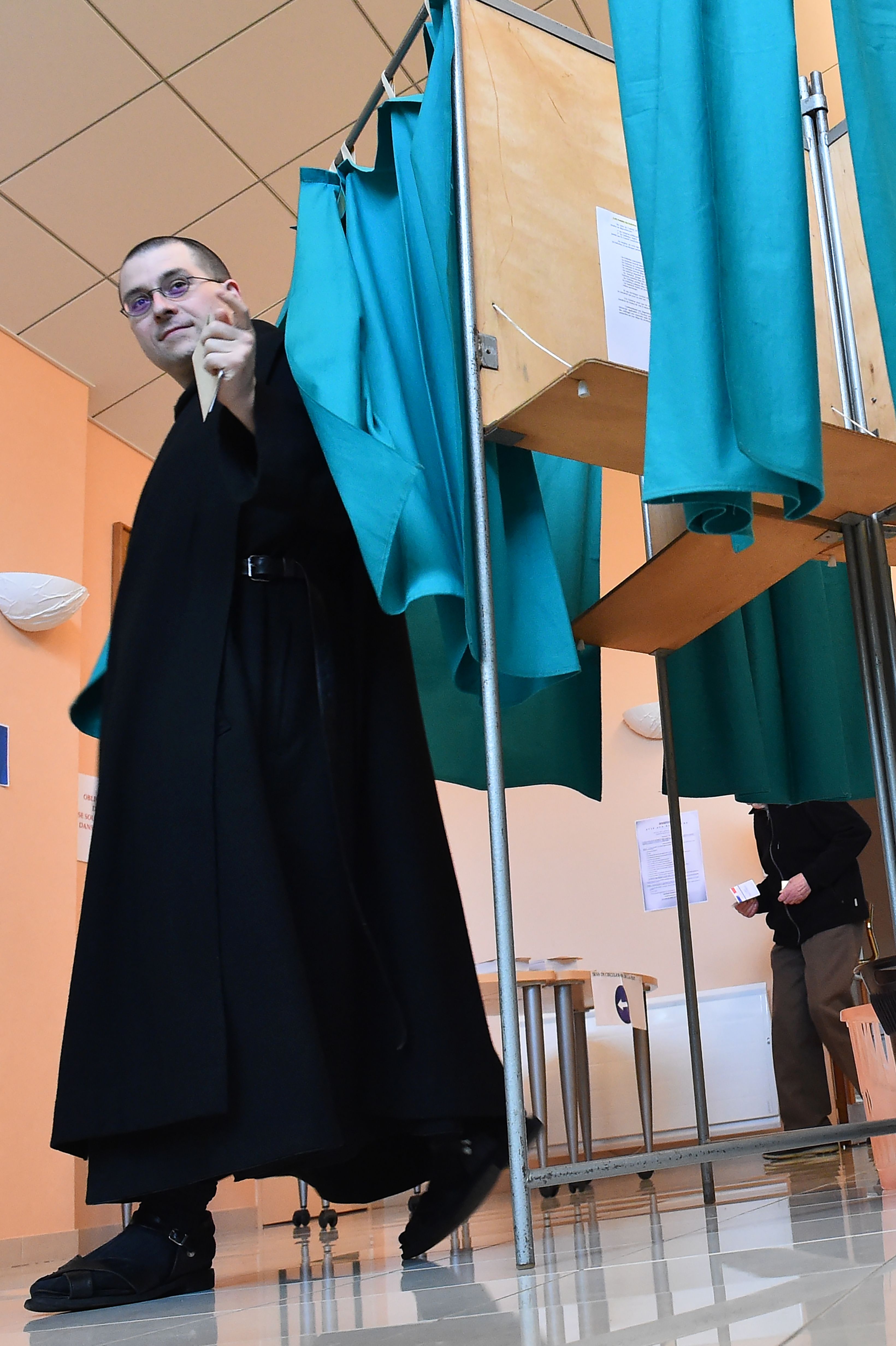 راهب يشير بيده للكاميرا عقب الإدلاء بصوته فى الانتخابات