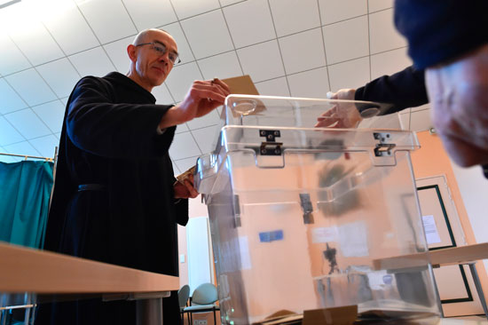 راهب يضع ورقة الاقتراع داخل صندوق الانتخابات