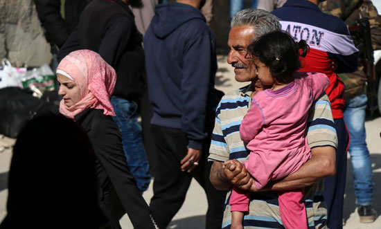 رجل يحمل طفلته لمغادرة حى برزة فى دمشق