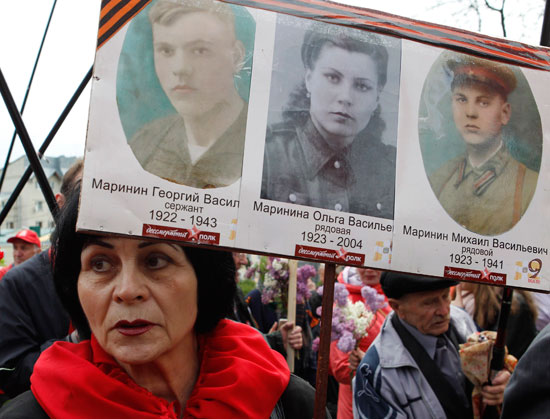 سيدة تحمل صور جنود روس فى مسيرة فوج الخالدين