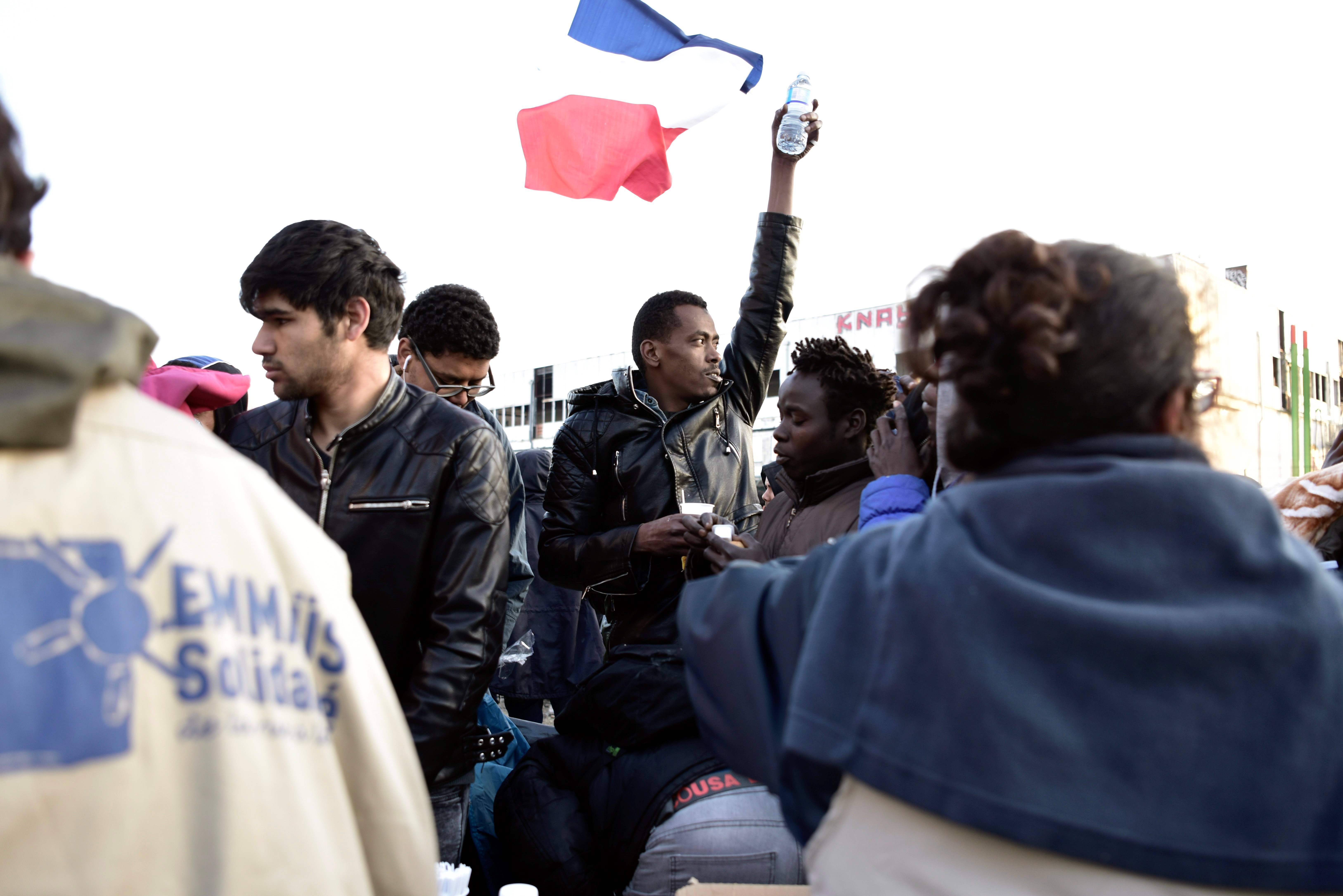 لاجئ يرفع علم فرنسا خلال اخلاء مخيم بباريس