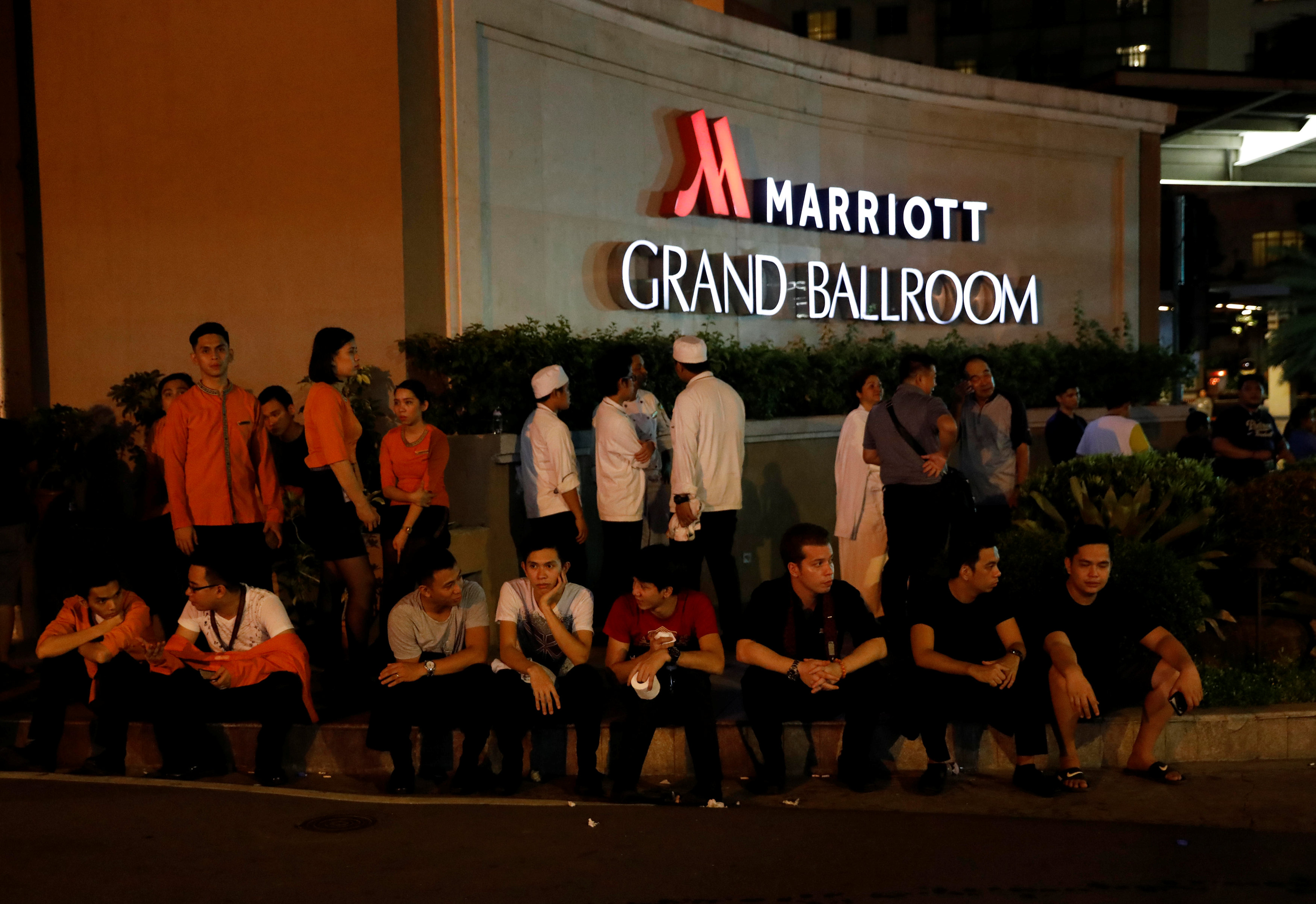 الموظفون الذين تم إجلاءهم عند مدخل فندق قرب مبنى منتجعات العالمى