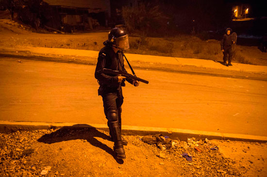أحد عناصر الشرطة المغربية يستخدم الغاز لمواجهة المحتجين