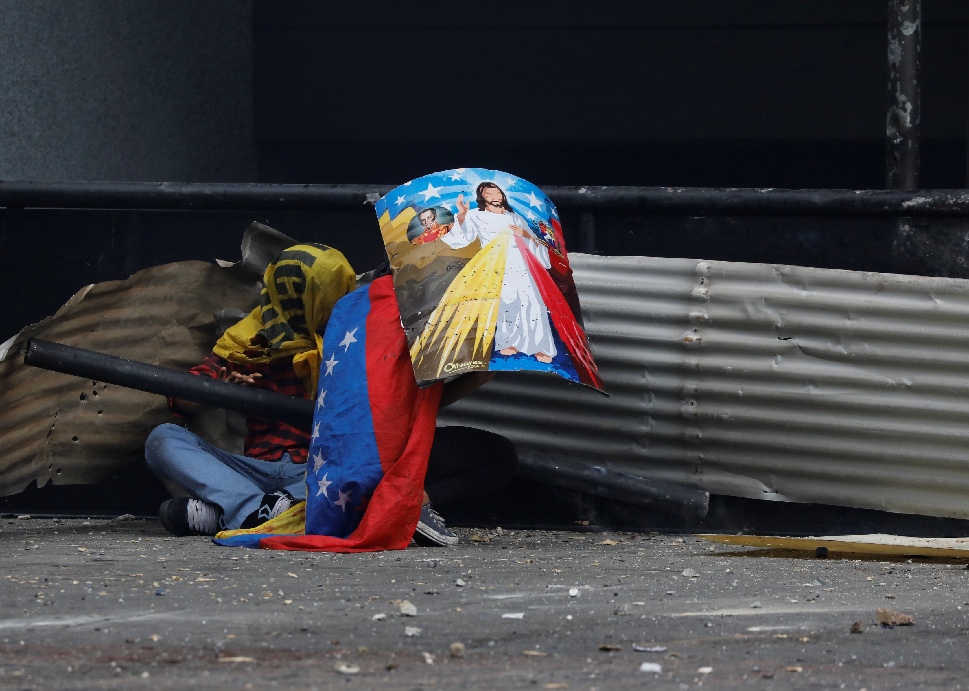 احتماء أحد المتظاهرين من طلقات الشرطة الفنزويلية