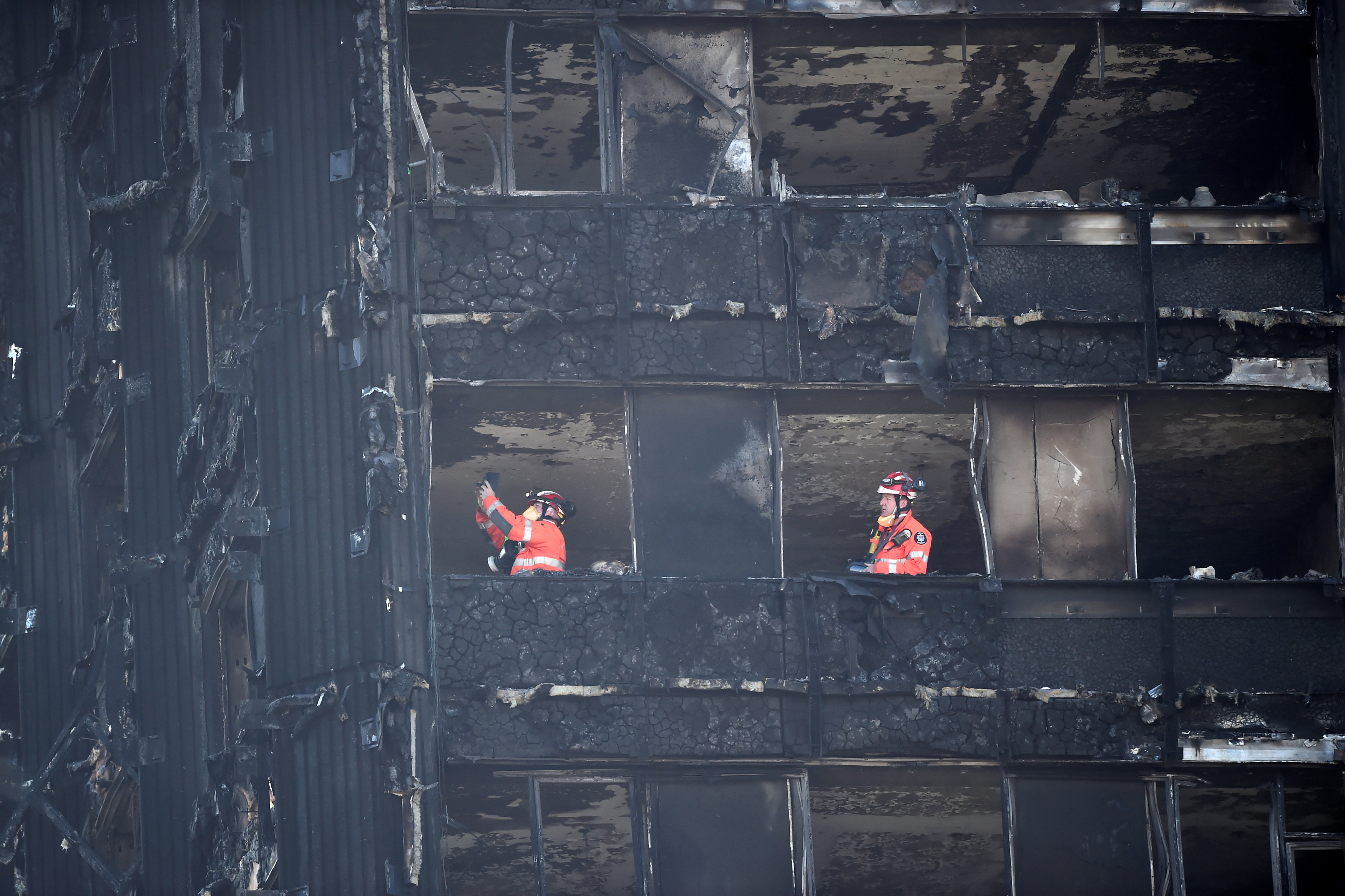 رجال الطوارئ يعاينون البرج المحترق فى لندن