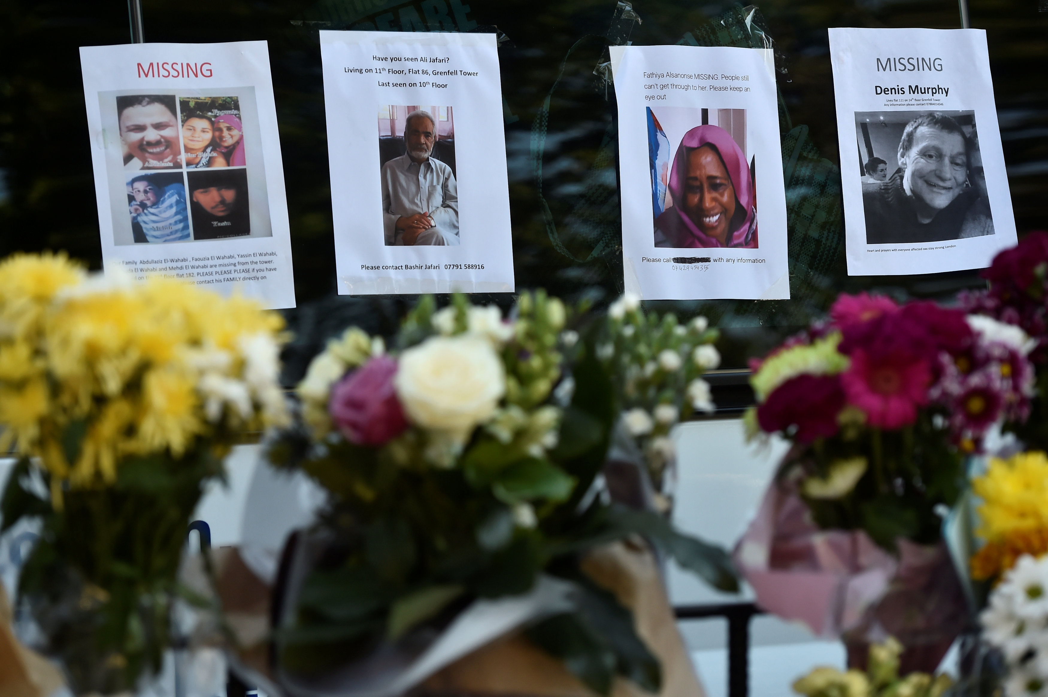 باقات زهور أمام صور ضحايا حريق لندن