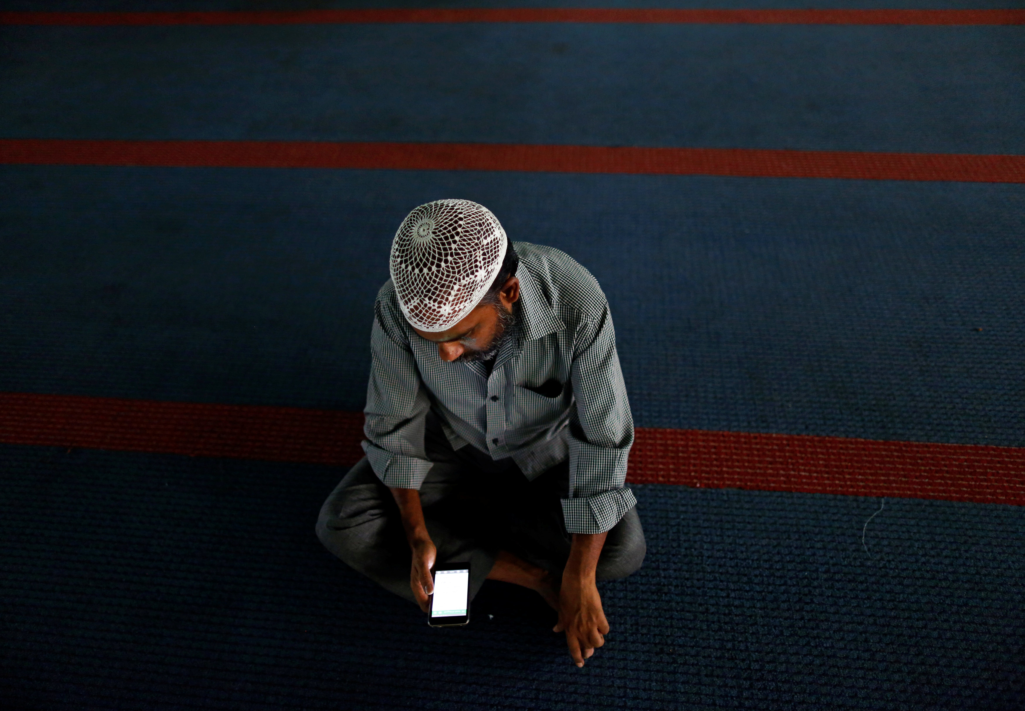 مسلم يقرأ القرآن من هاتفه المحمول