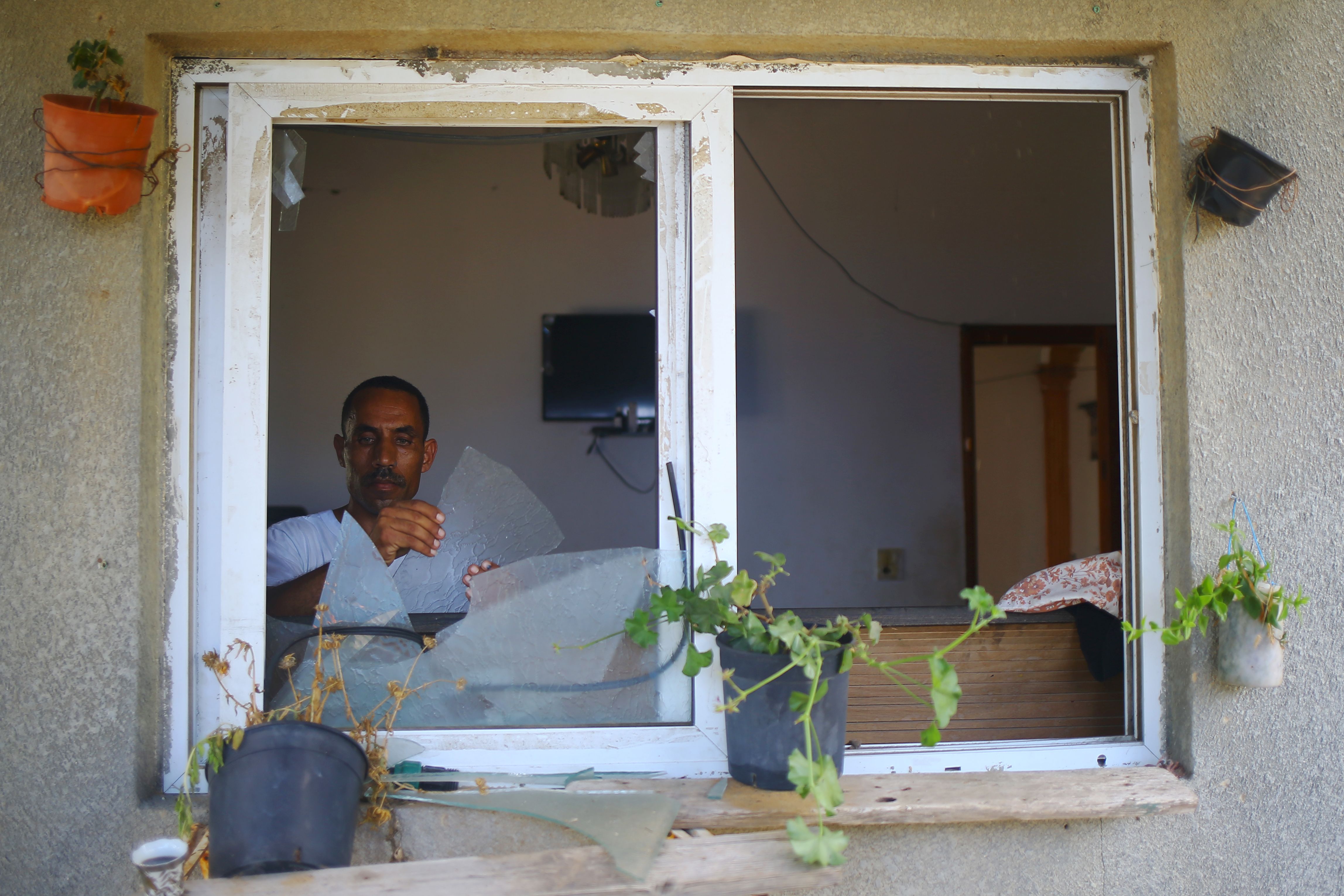 رجل يزيل الزجاج المحطم إثر القصف الإسرائيلى