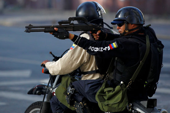 شرطى فنزويلى يصوب سلاحه تجاه المحتجين