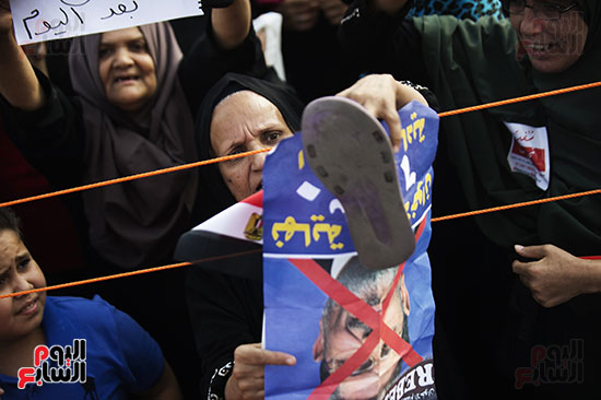سيدة عجوز ترفع "الشبشب" على صورة مرسى