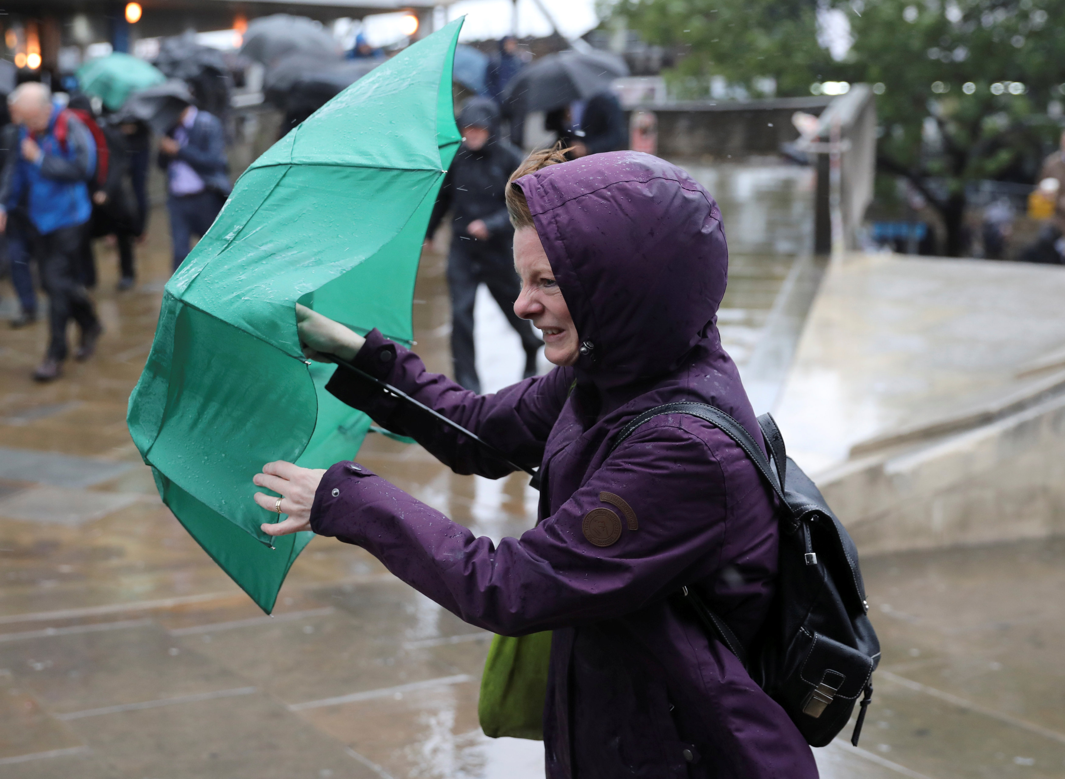 مواطنة بريطانية تحاول الإمساك بمظلتها