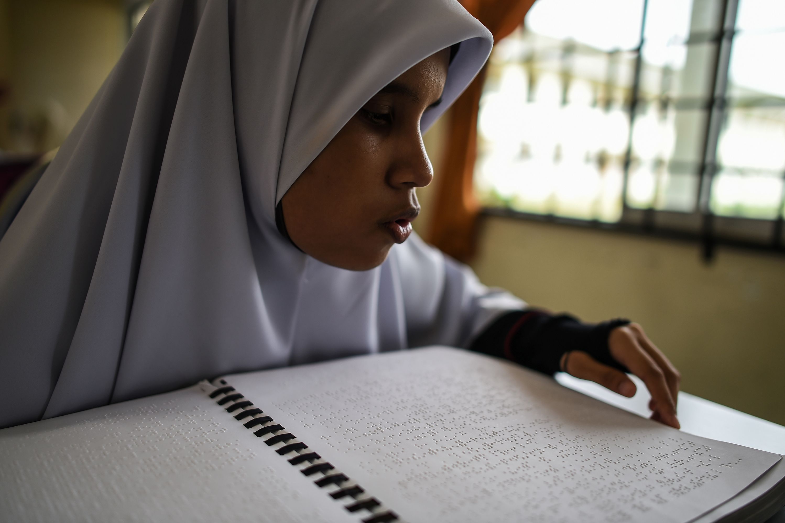 محاولة فتاة ماليزية التغلب على اعاقة البصر لقرأة القرآن فى رمضان