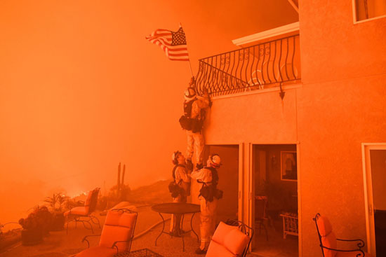  جندى يرفع علم أمريكا من واجهة أحد المبانى فى منطقة الحرائق