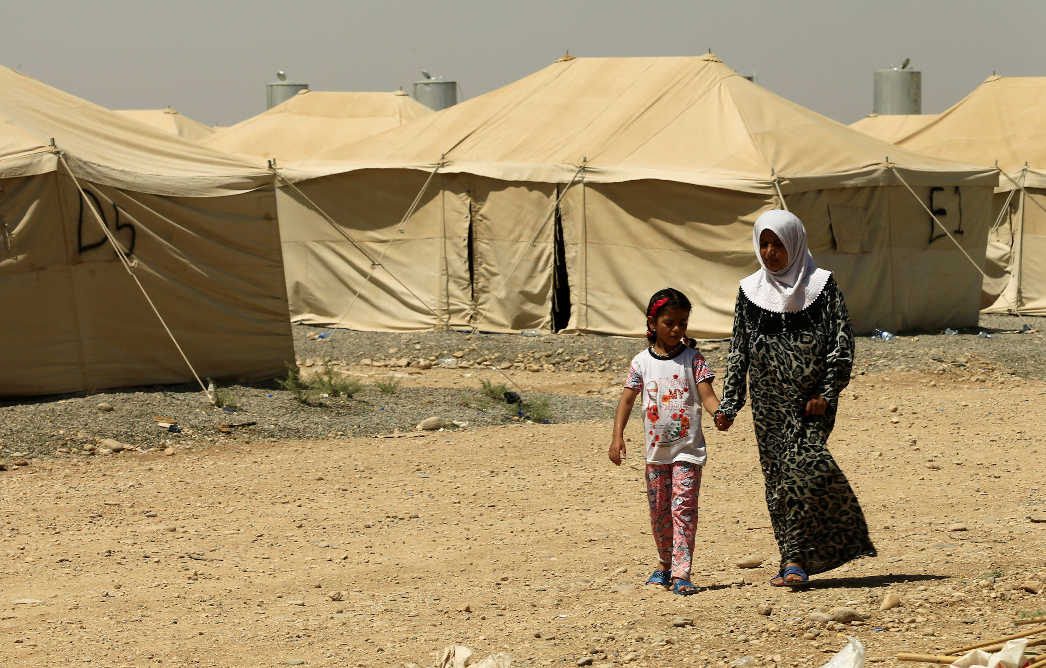 سيدة وابنتها تسيران داخل مخيم لأسر مقاتلو داعش فى الموصل
