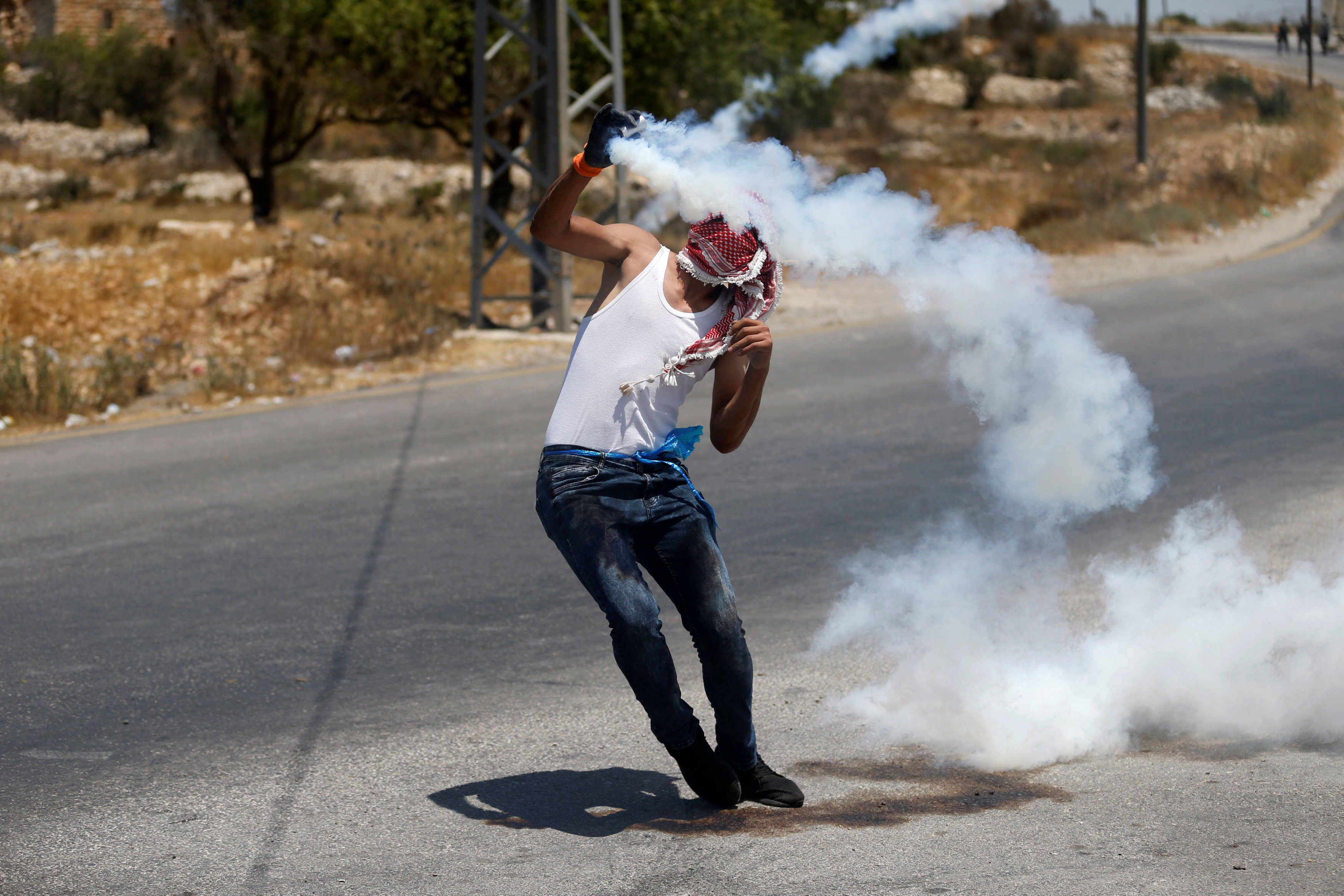شاب فلسطينى يلقى القنابل المسيلة للدموع