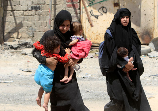 سيدتان عراقيتان تغادران البلدة القديمة بالموصل برفقة أطفالهم